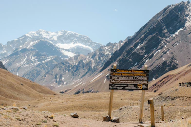 Wooden signpost in a mountain valley with snowy peaks