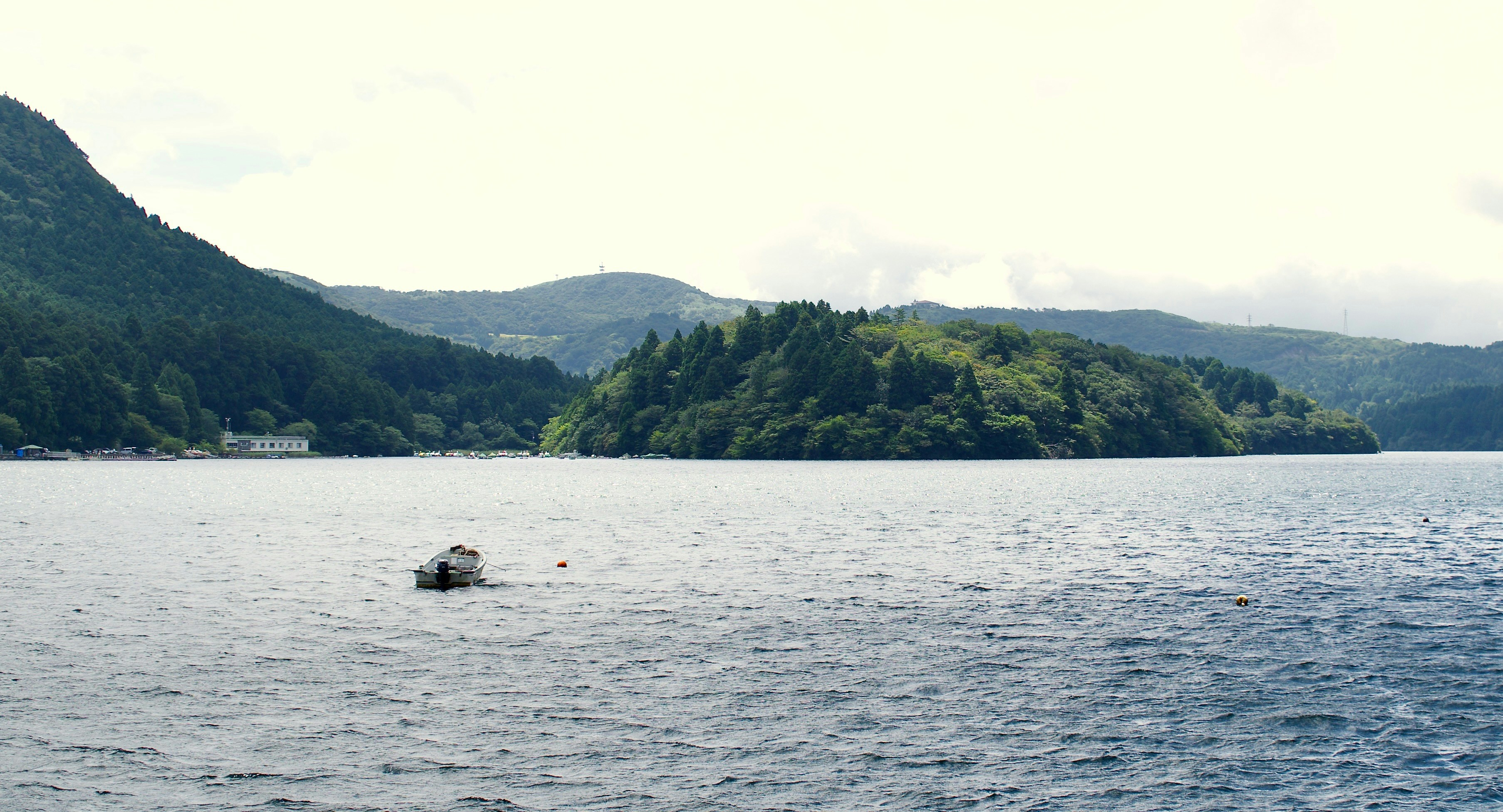 Boat on a large lake with forested hills.