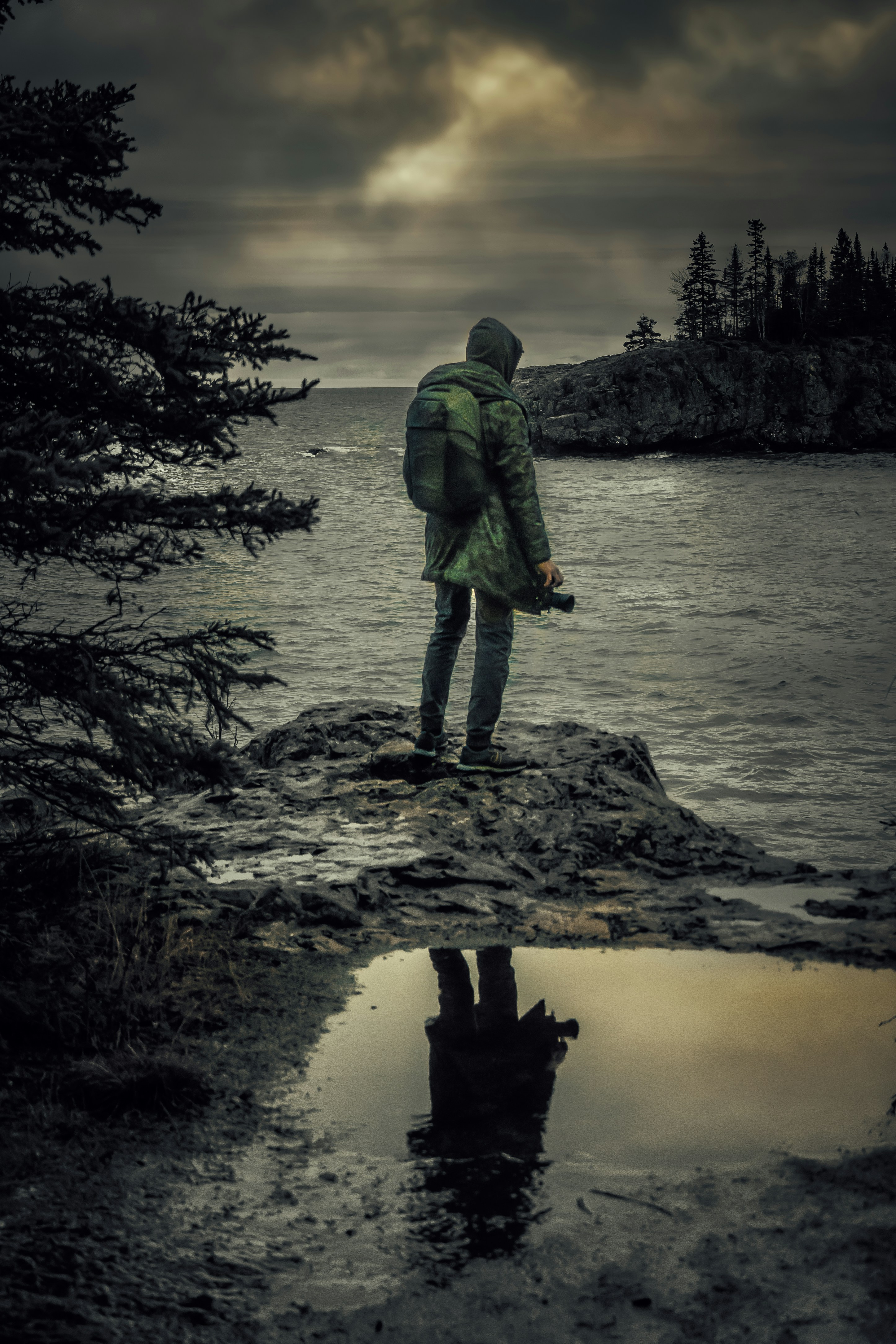 Person with backpack on rocky shore overlooking ocean