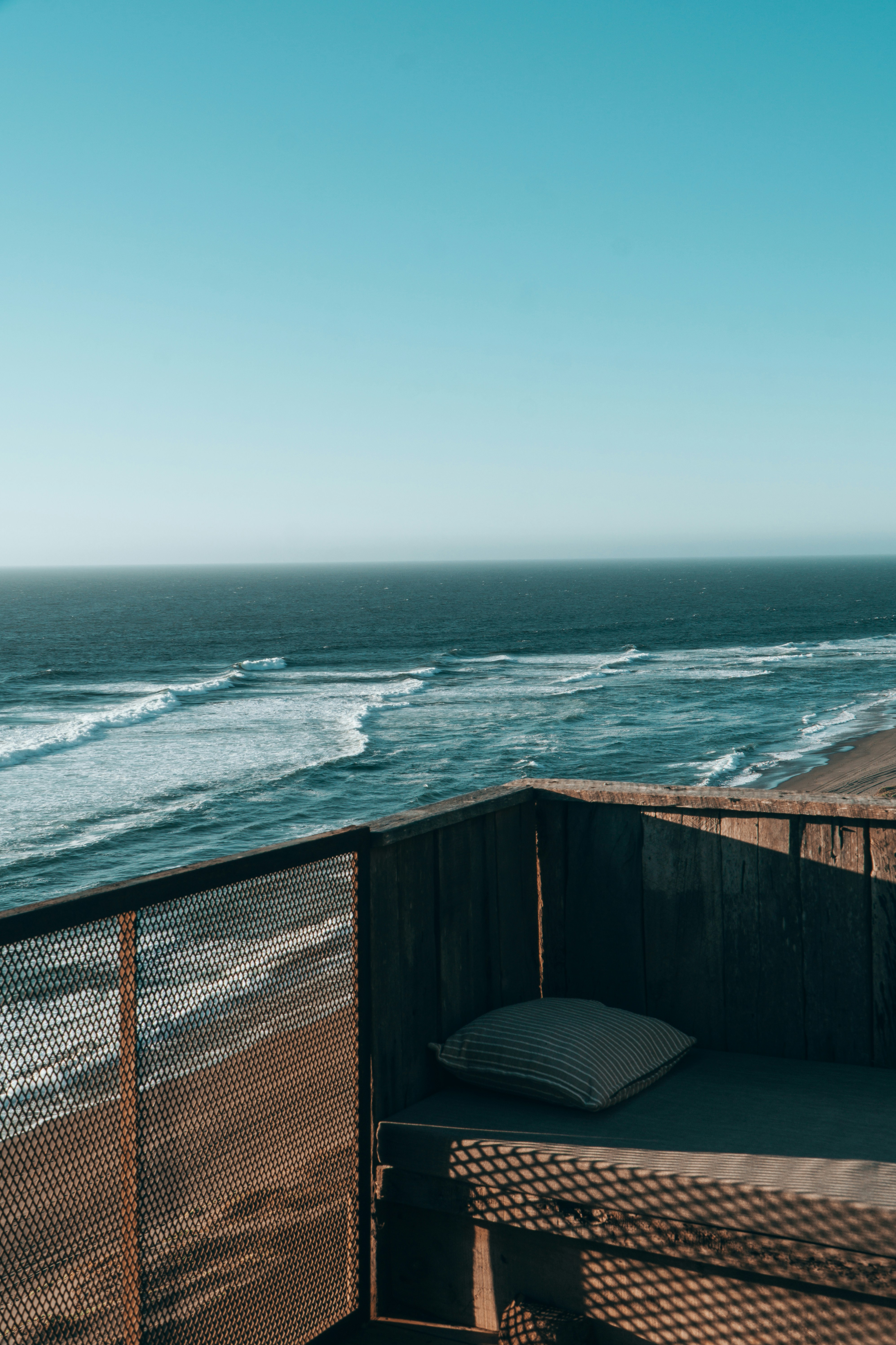 Ocean waves crash on beach from wooden deck.