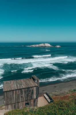 Rustic wooden cabin overlooking ocean waves and island
