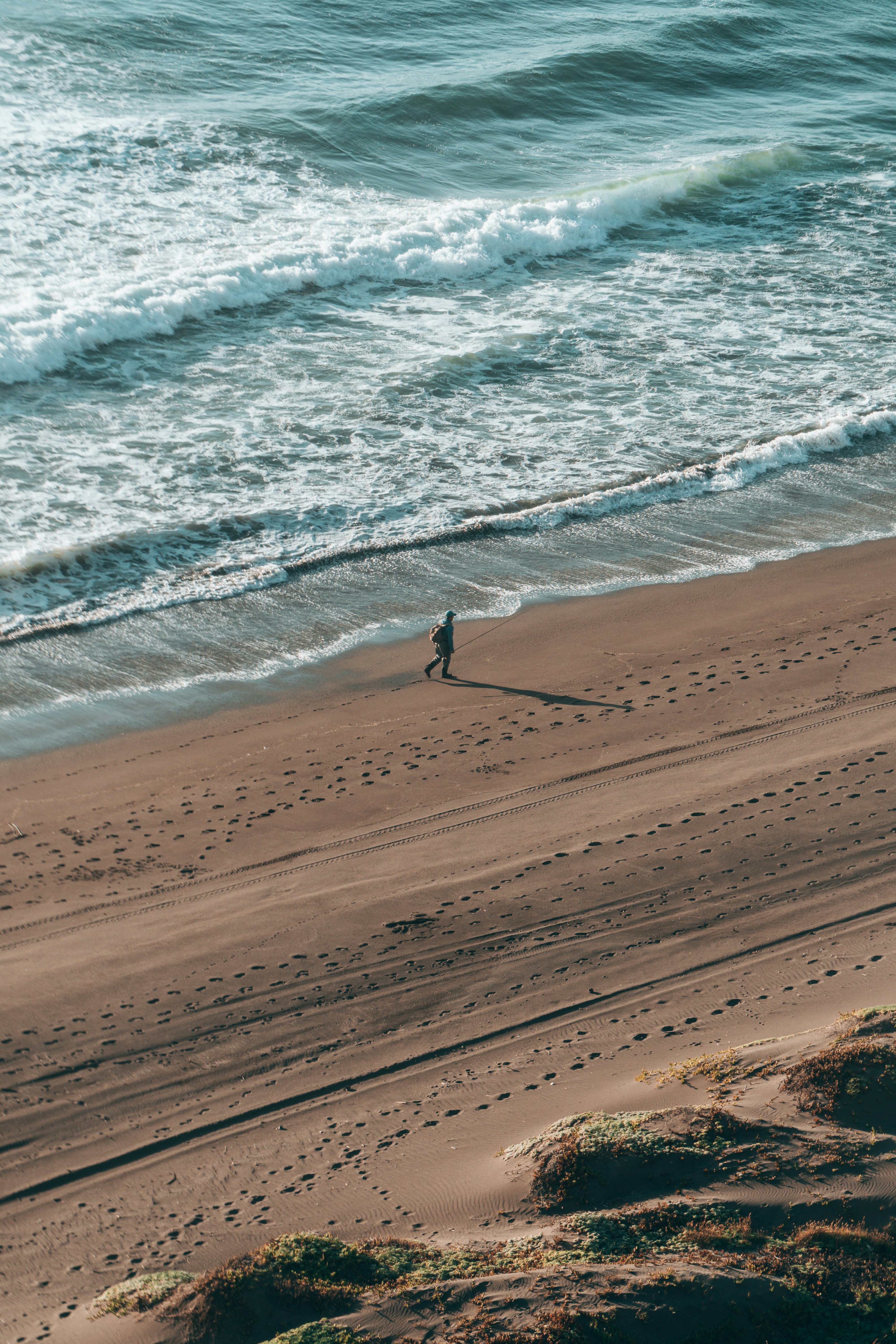 A person walks along a sandy beach by the ocean