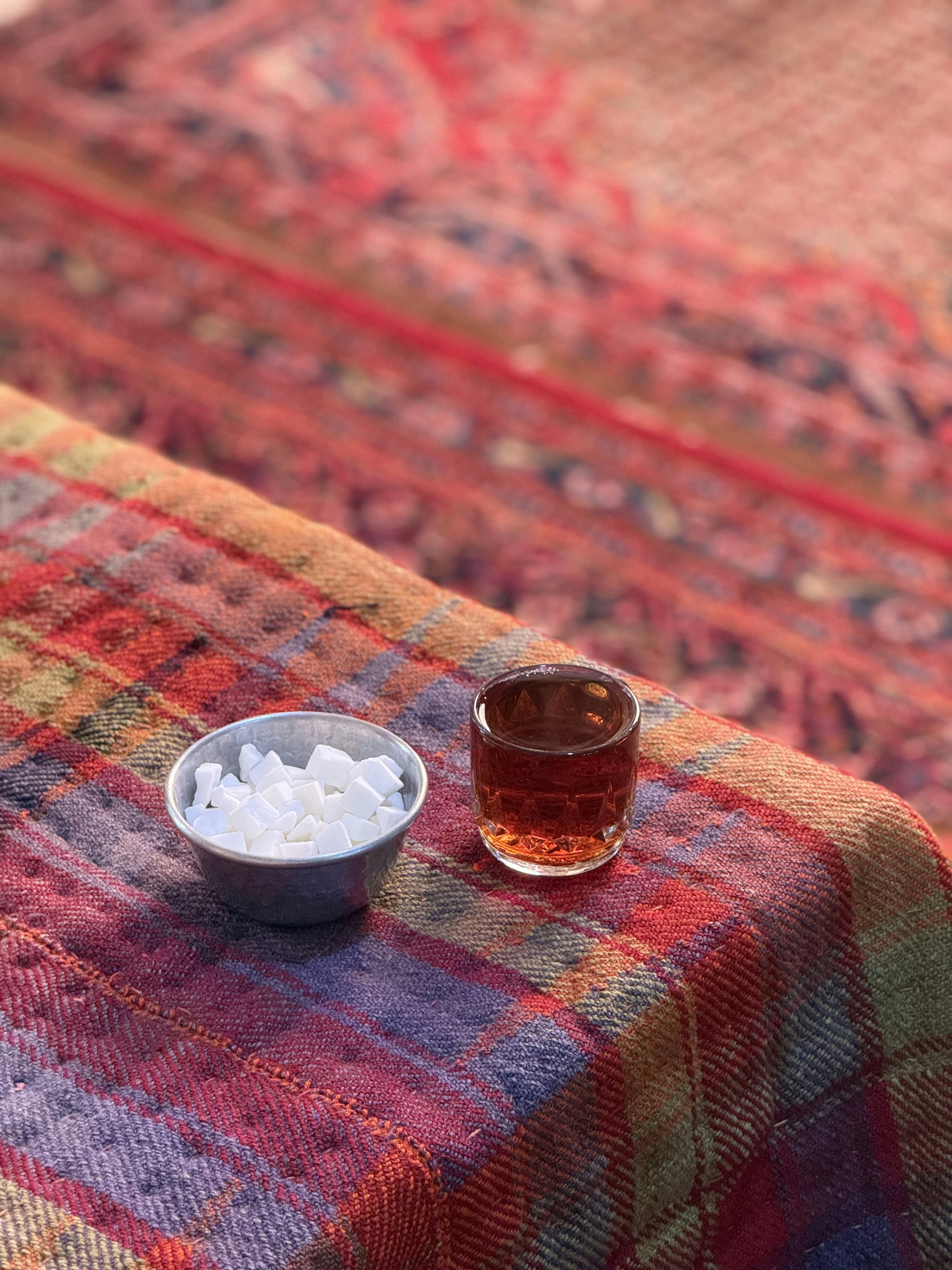 Petit bol de morceaux de sucre à côté du liquide ambré.