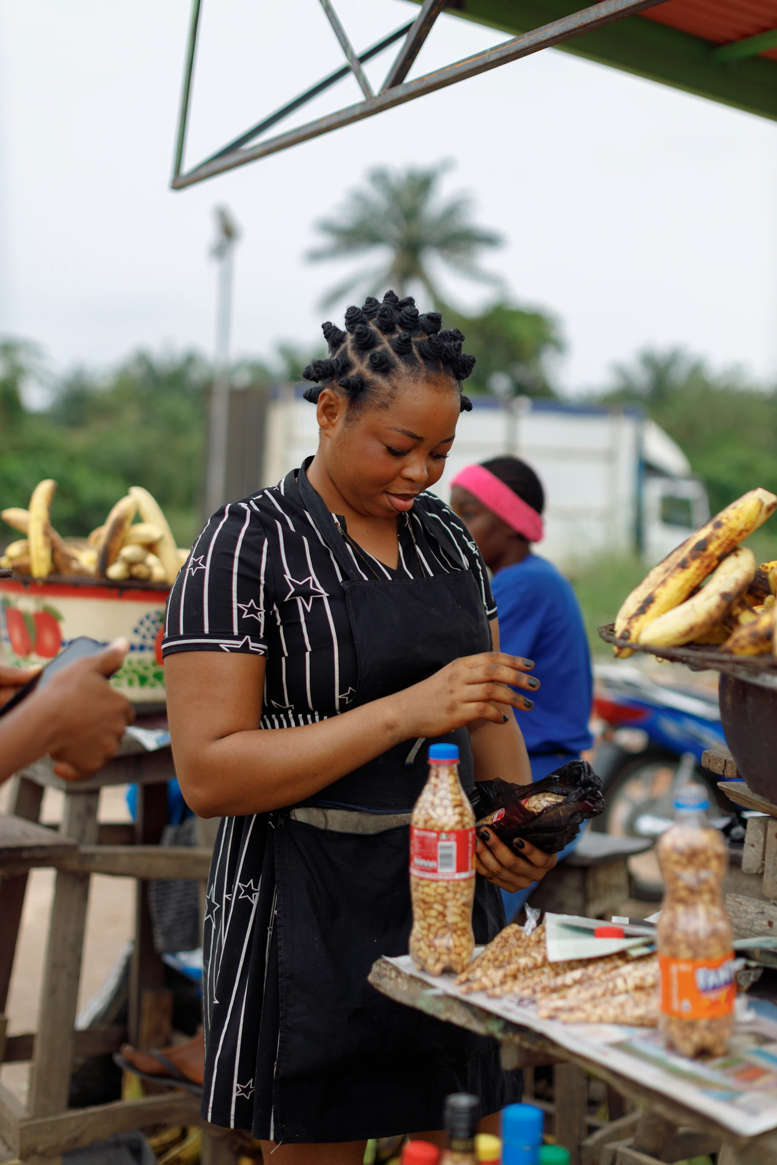A woman preparing food at an outdoor market stall