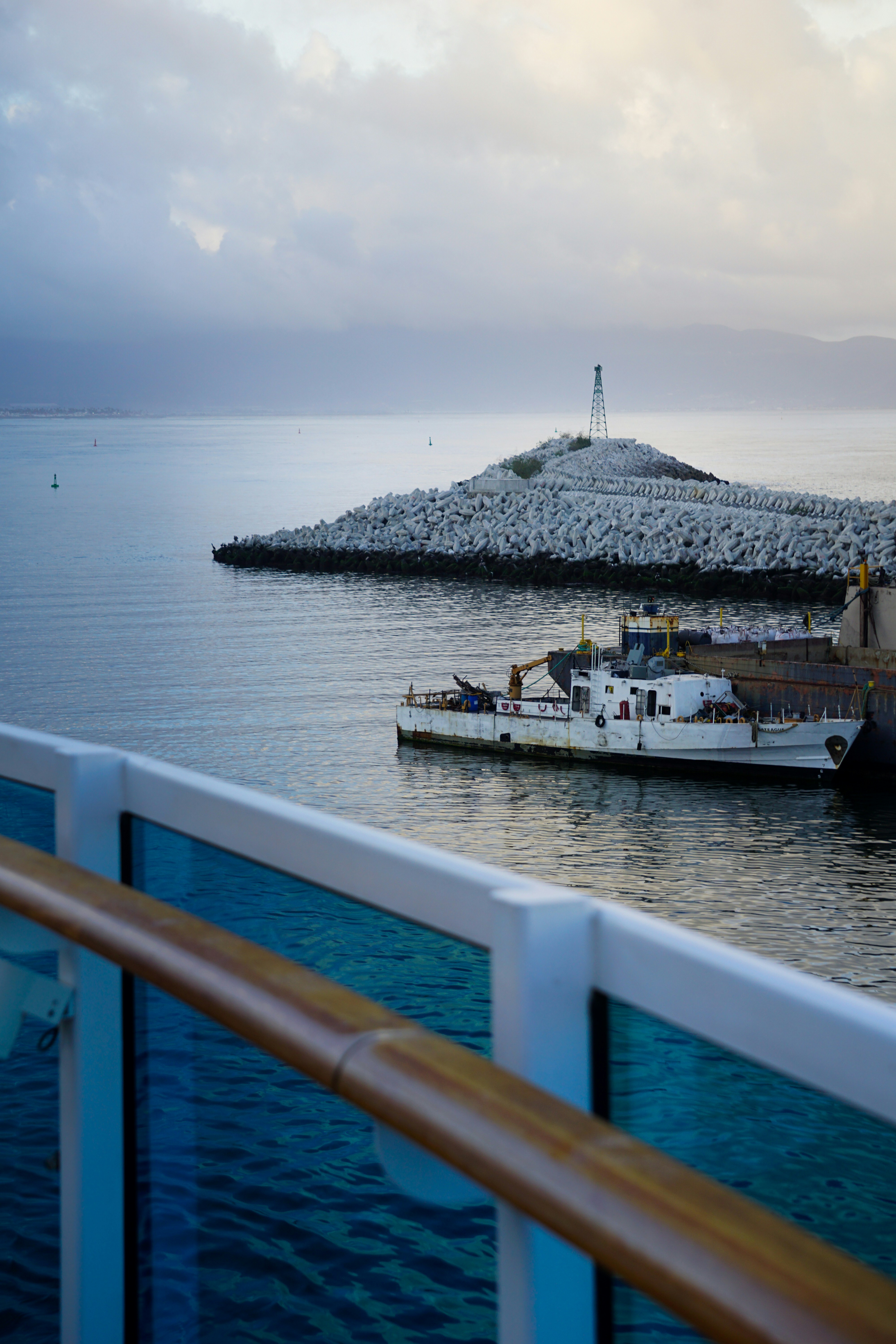 A small boat docks near a rocky island lighthouse.