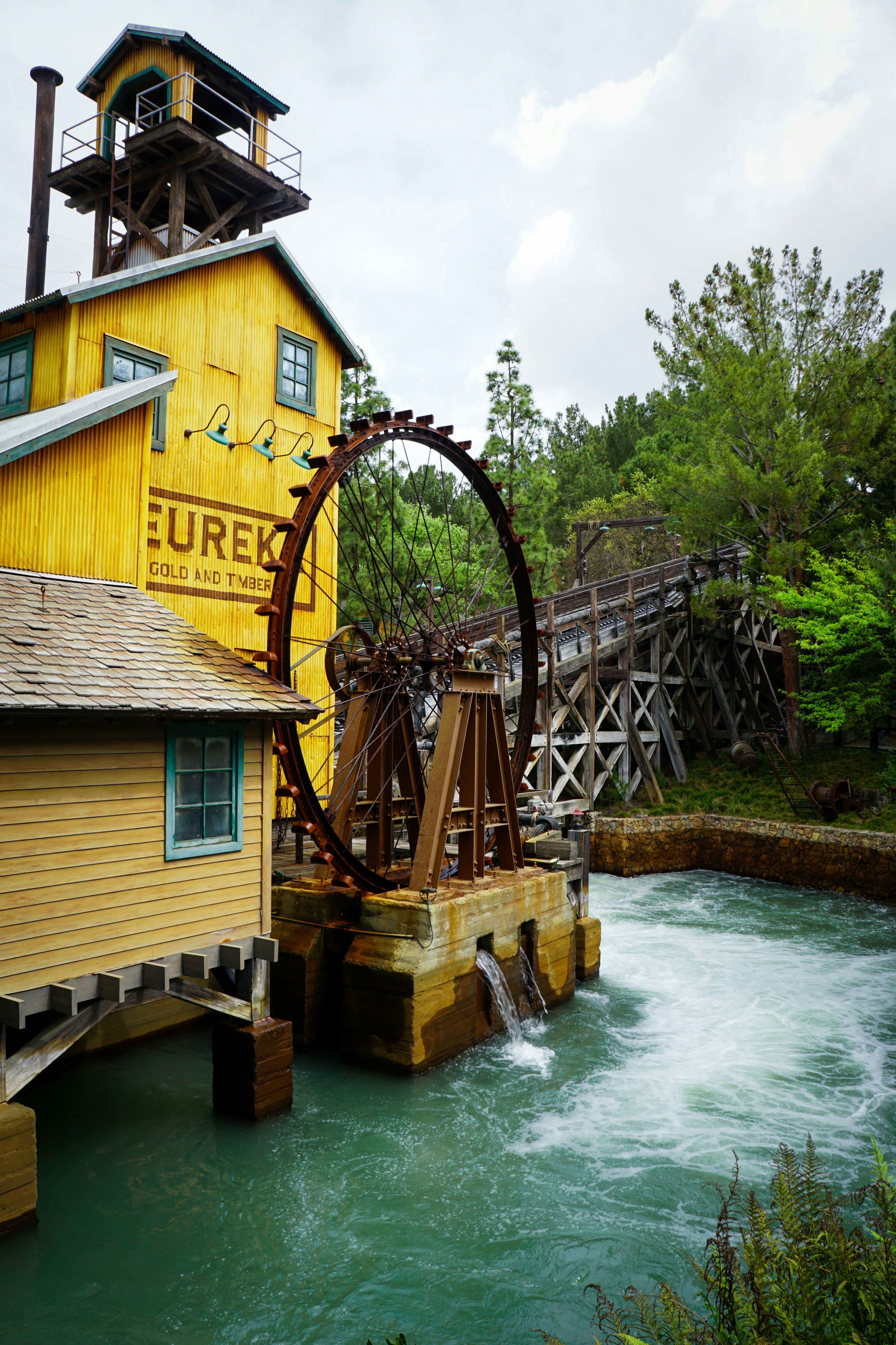 Yellow building with water wheel beside rushing river