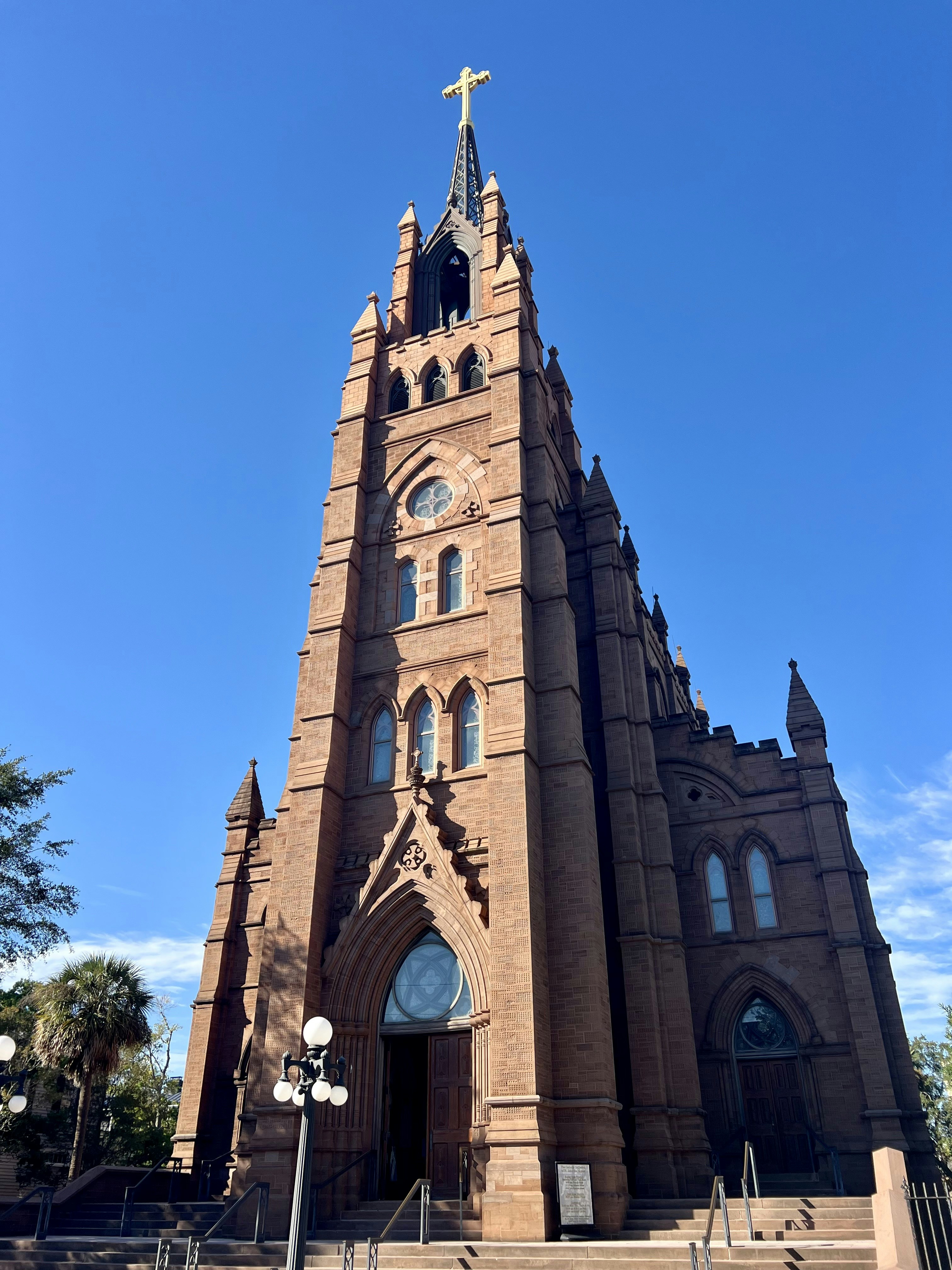 Hohe Backsteinkirche mit einem Kreuz vor blauem Himmel