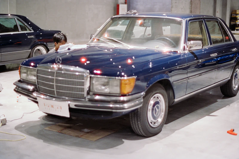 A dark blue vintage Mercedes-Benz sedan parked indoors