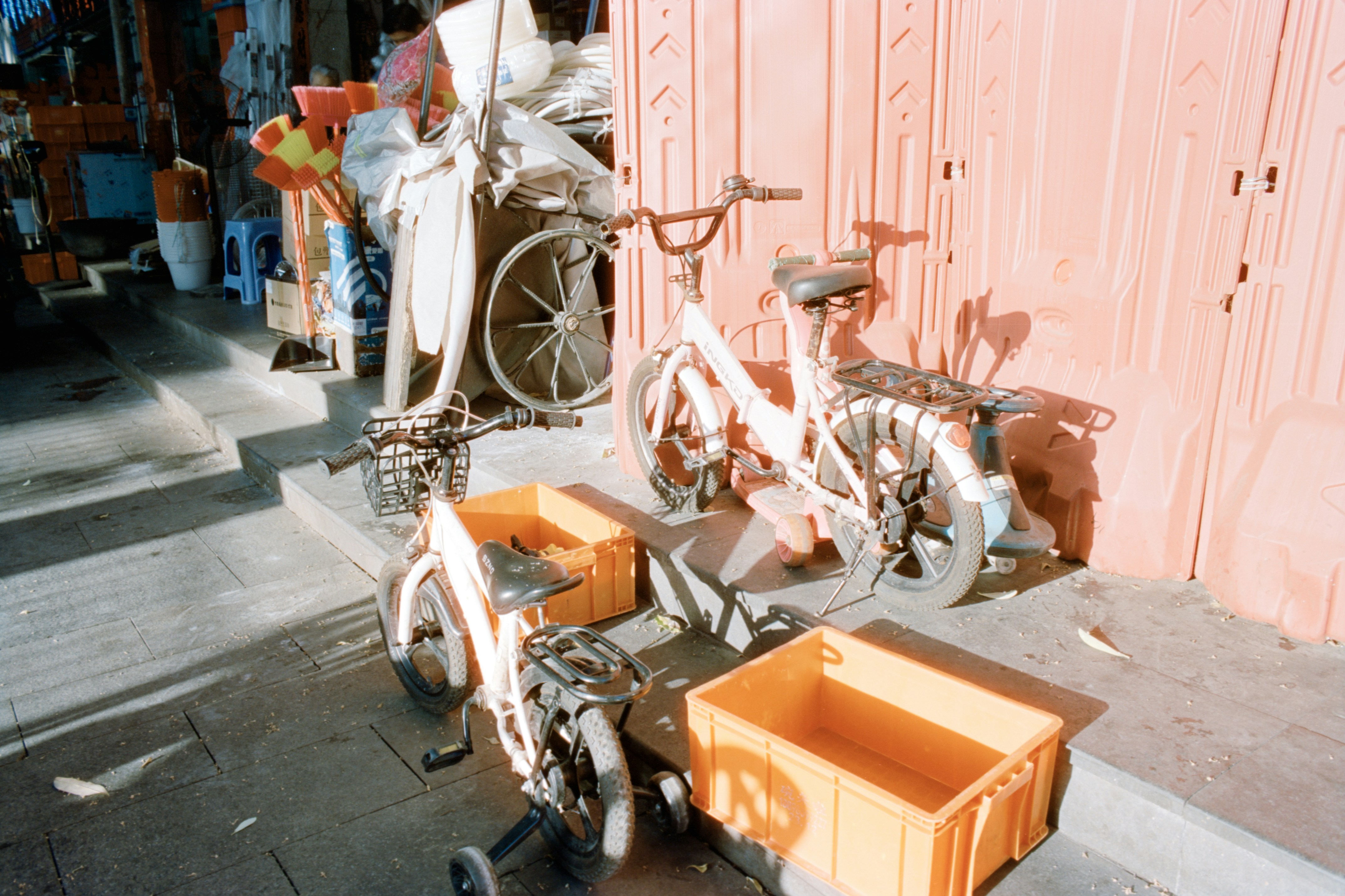 Two bicycles with orange crates parked near wall