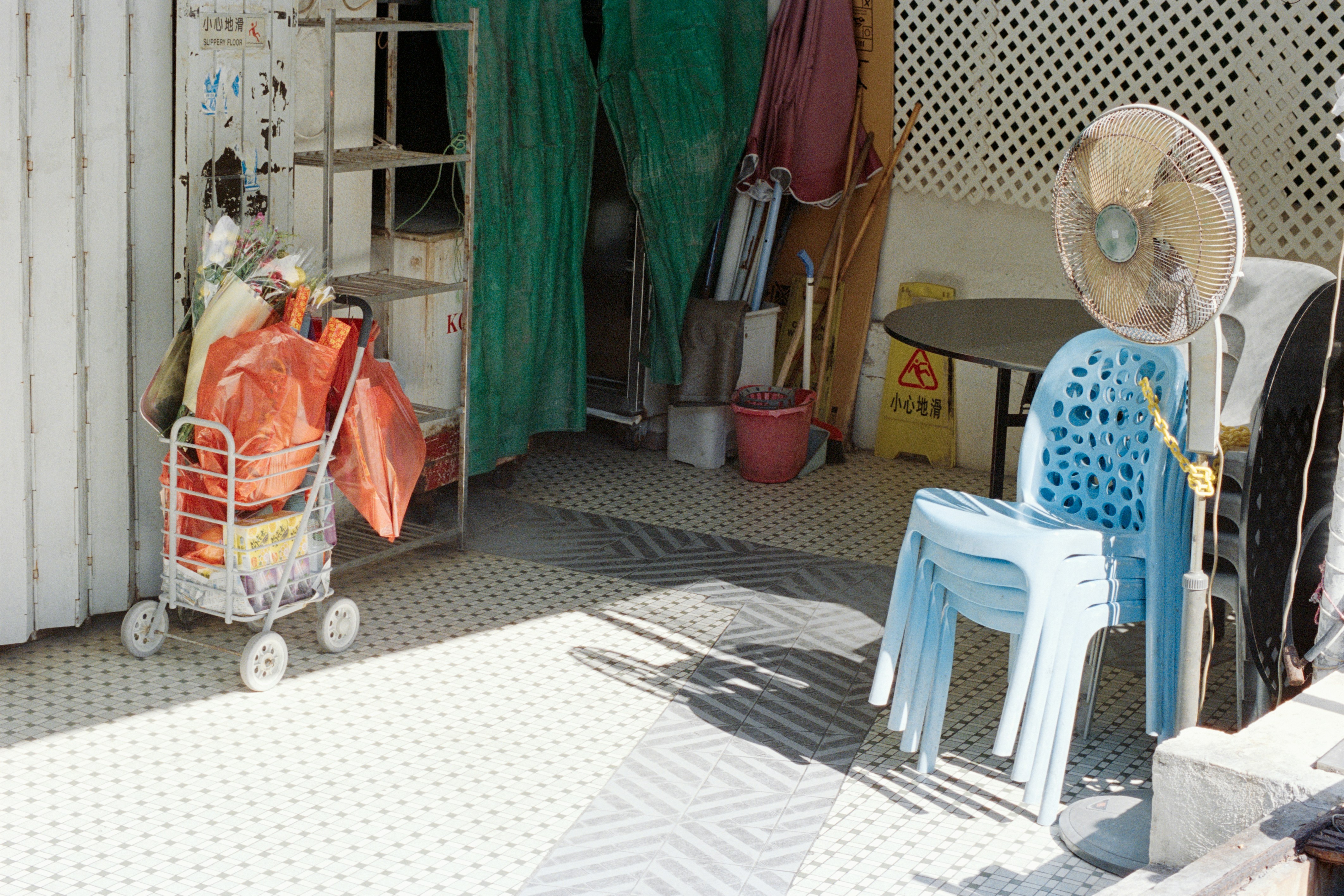 Stacked chairs and a fan outside a building entrance