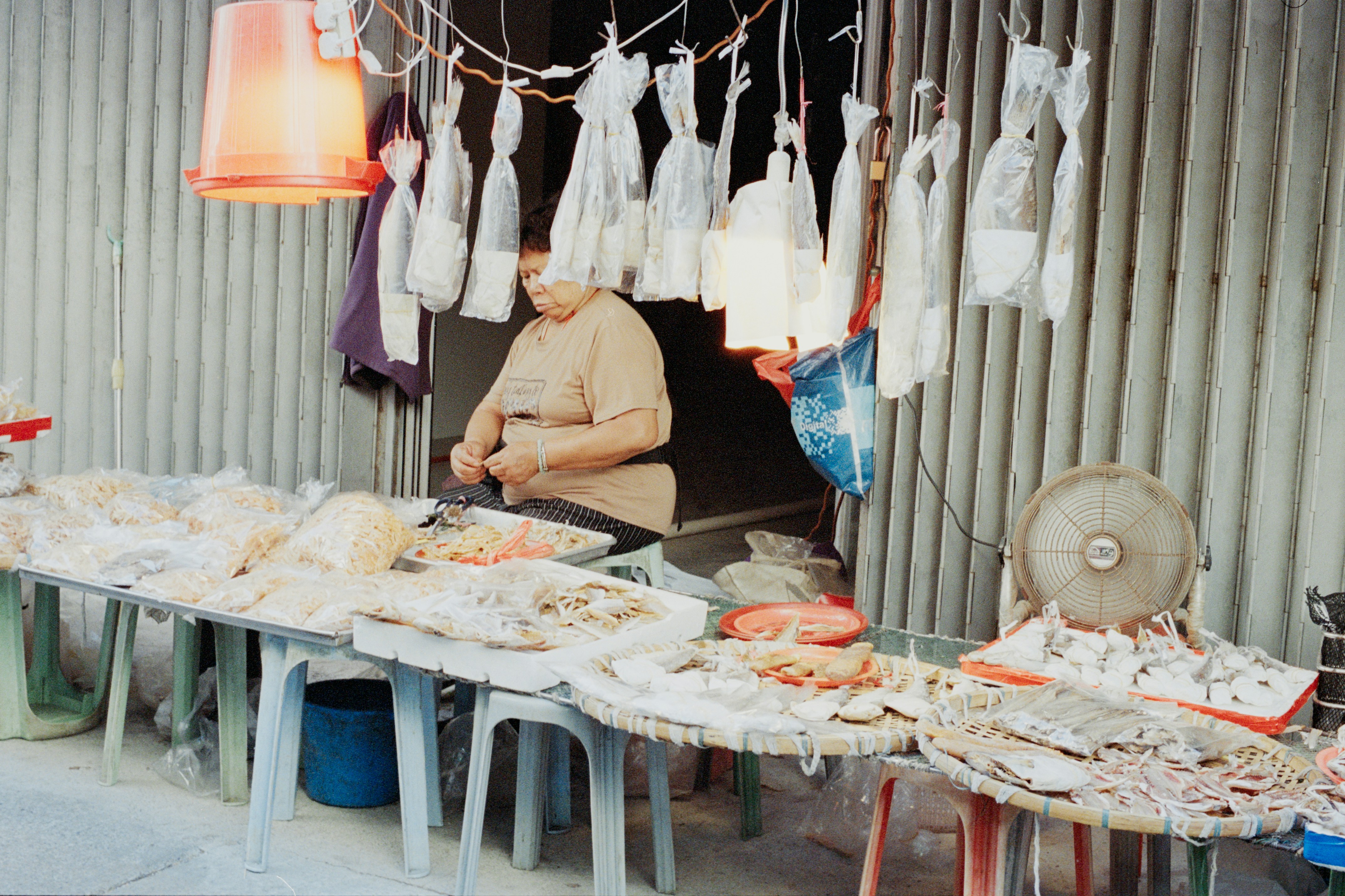 Vendor selling fish at an outdoor market stall.