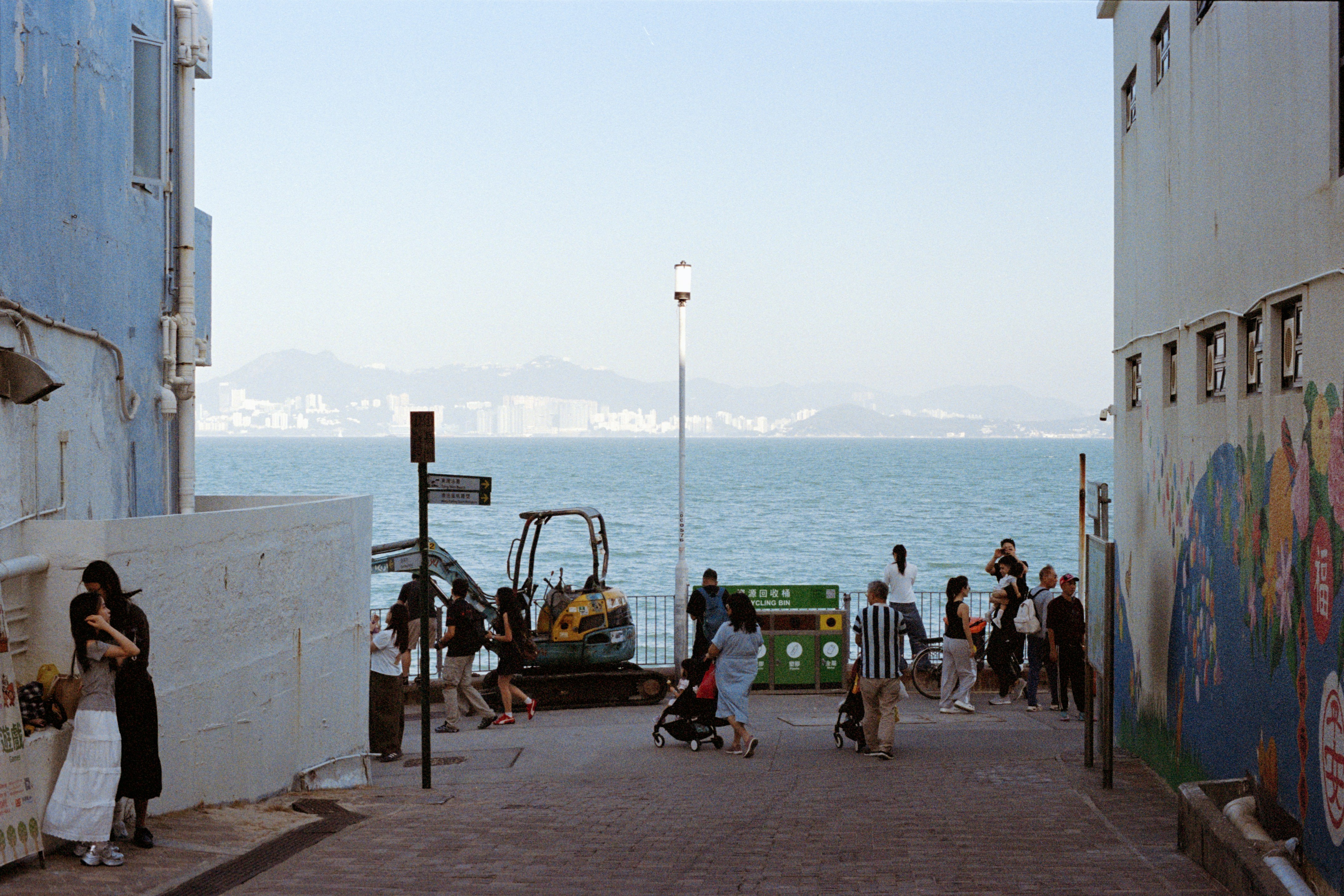 People gather by the sea with buildings in distance