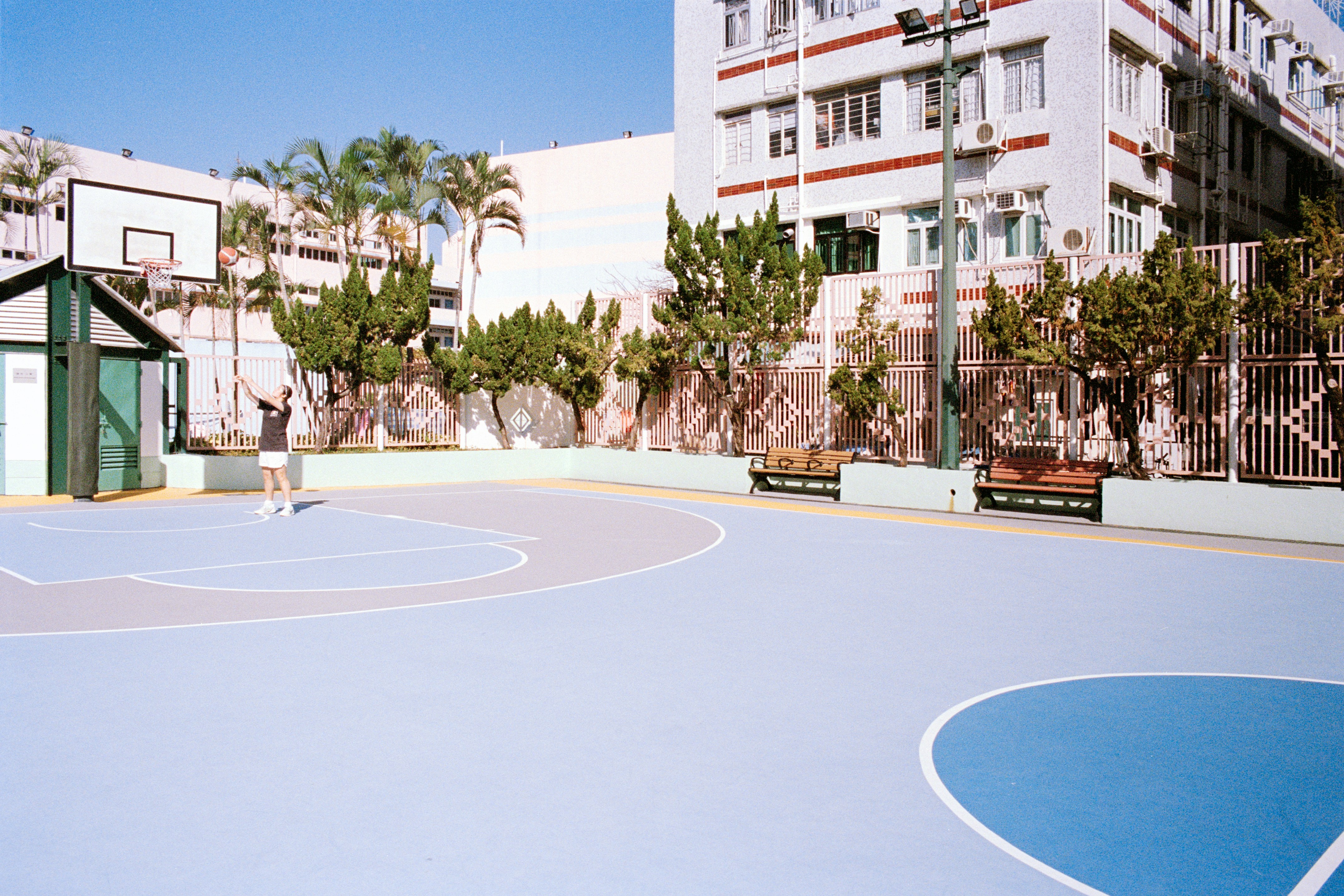 A person playing basketball on an outdoor court.