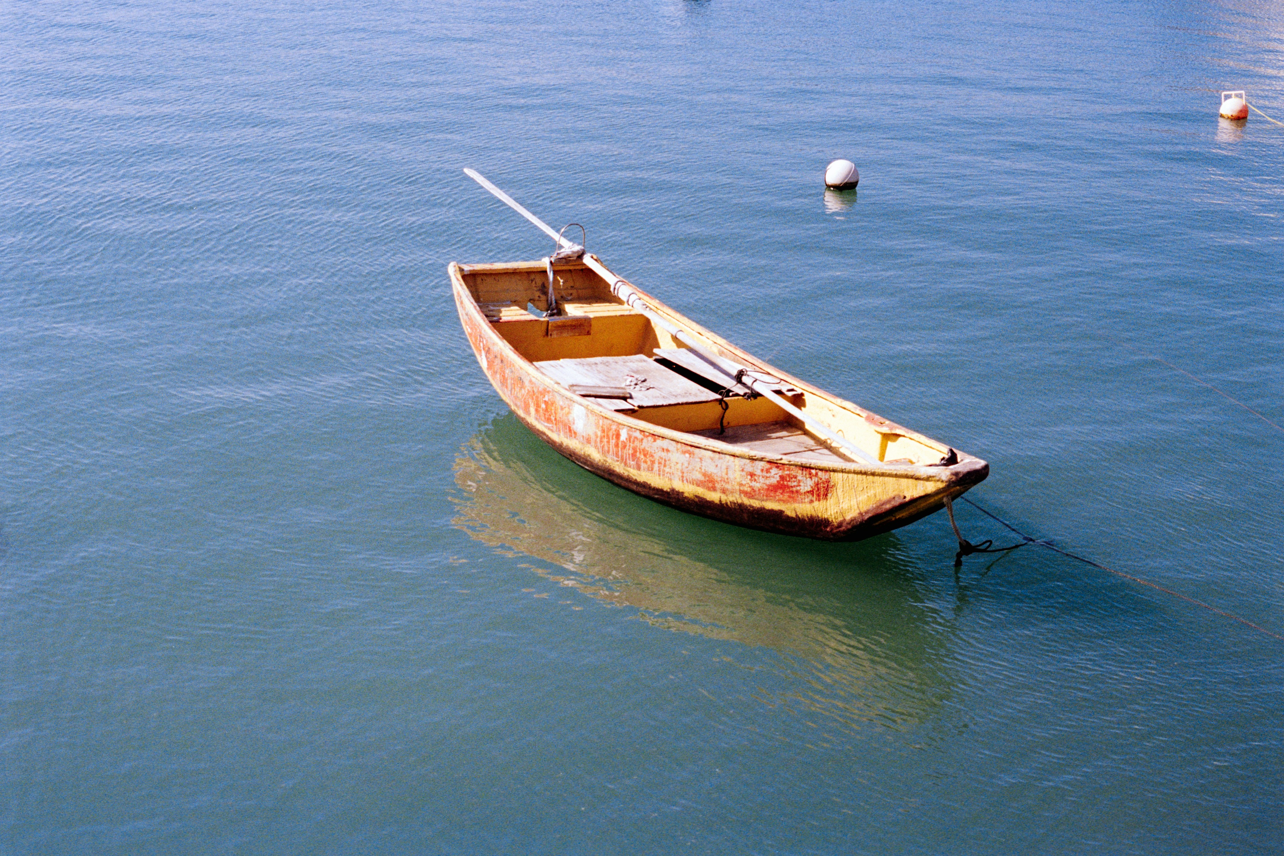 A small wooden boat floats on blue water.