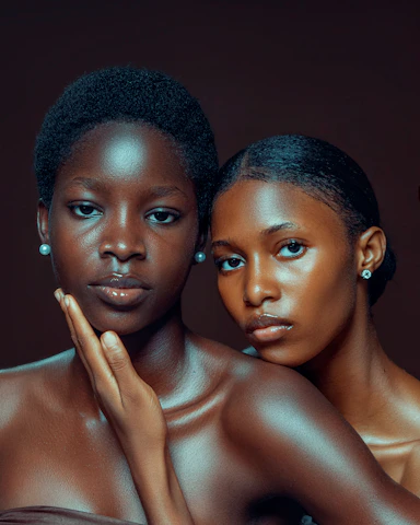 Two young women with dark skin and pearl earrings.