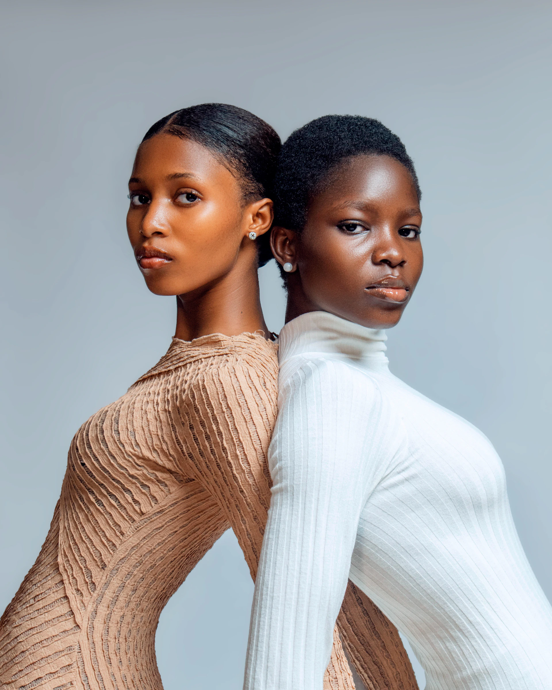 Two young women standing back to back.