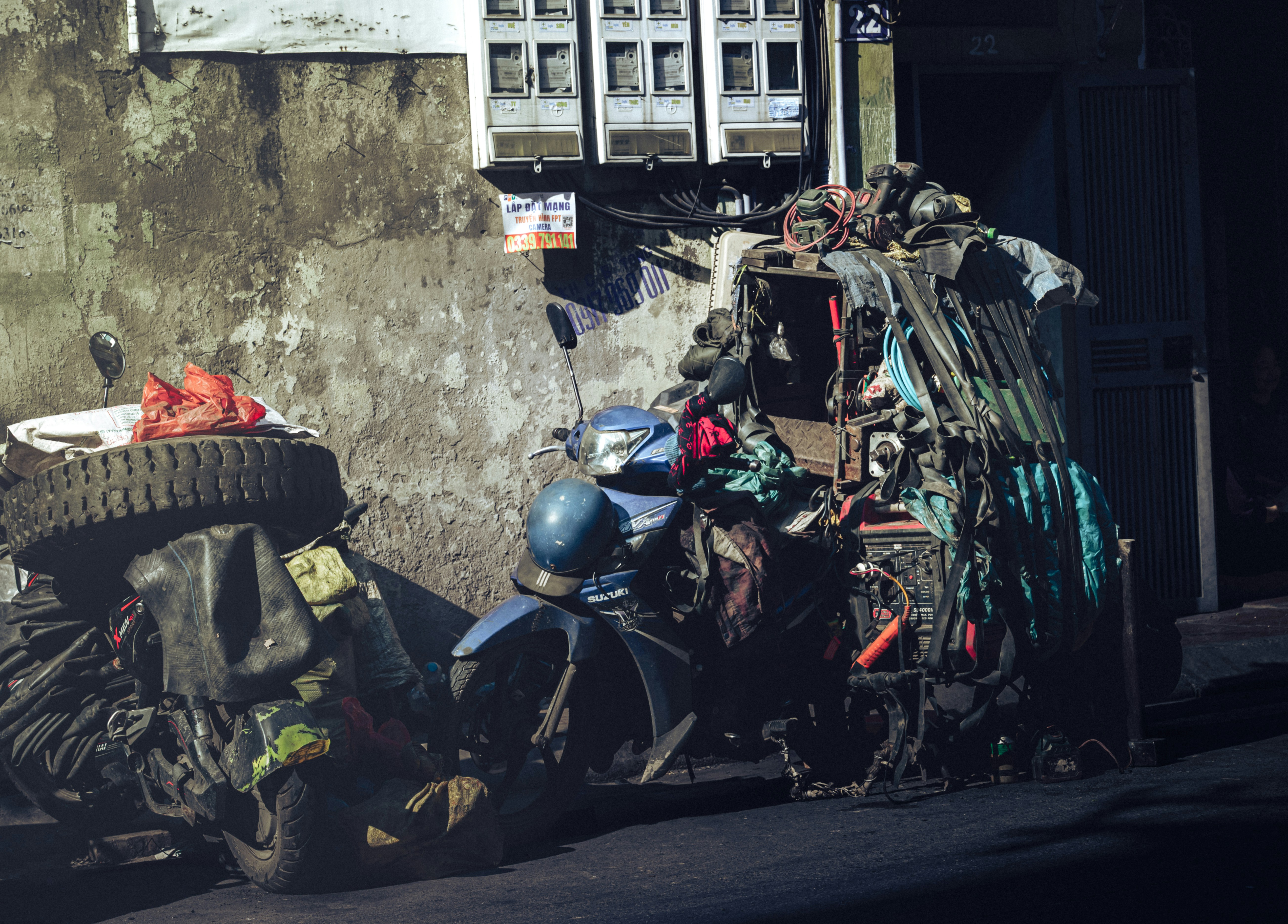 A heavily loaded scooter parked against a wall.