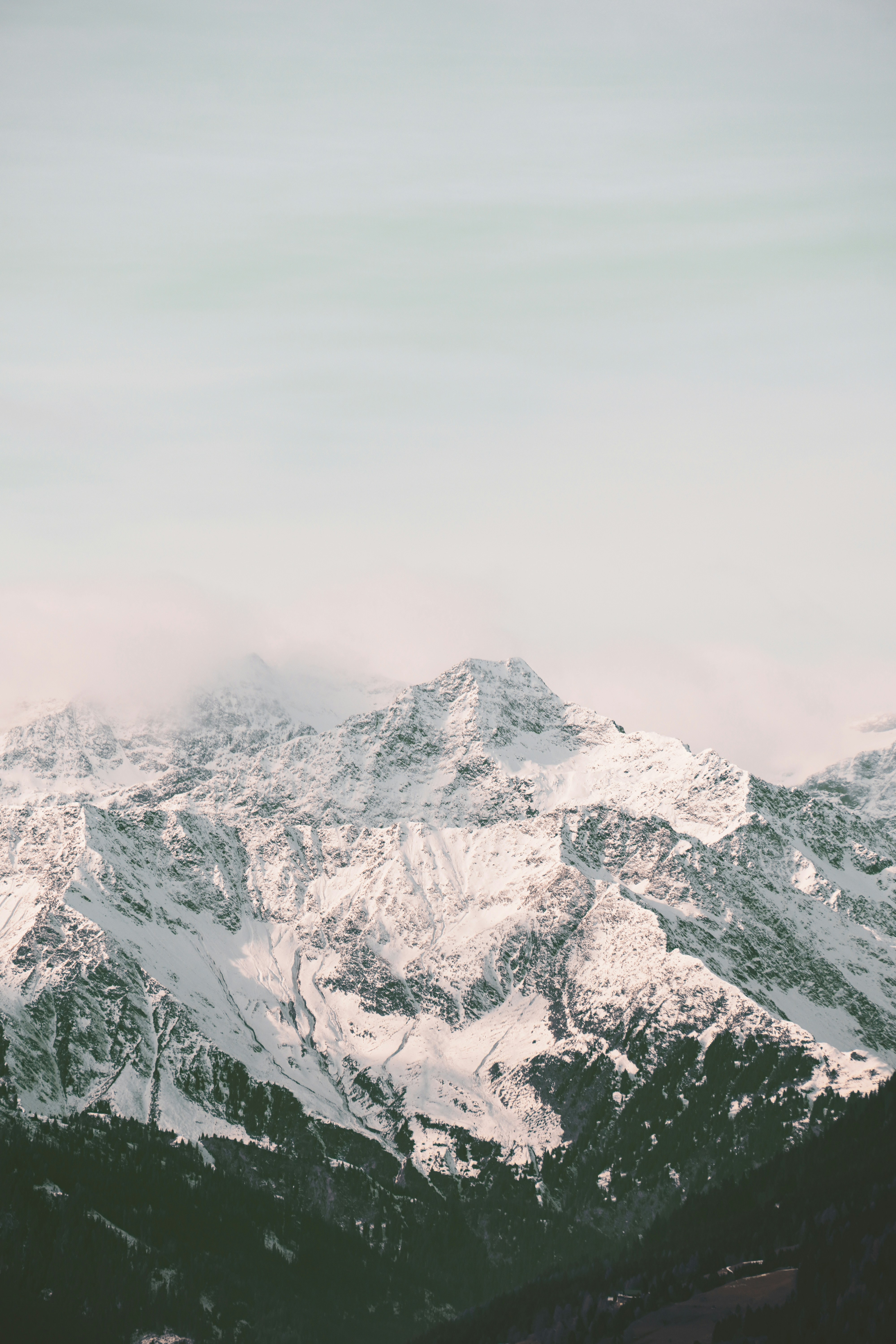 Snow-covered mountains under a pale sky