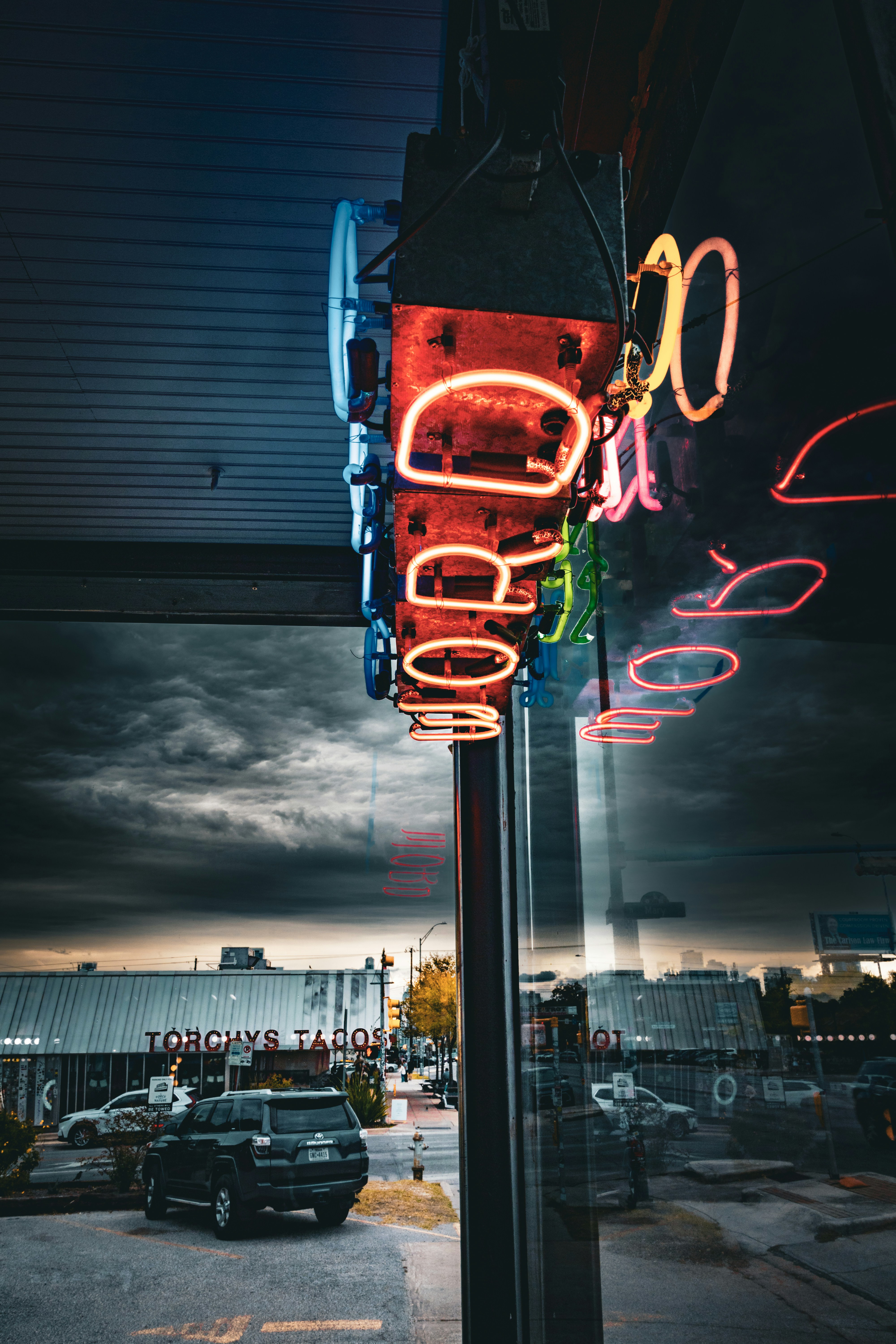 Neon sign reflects in a window at dusk