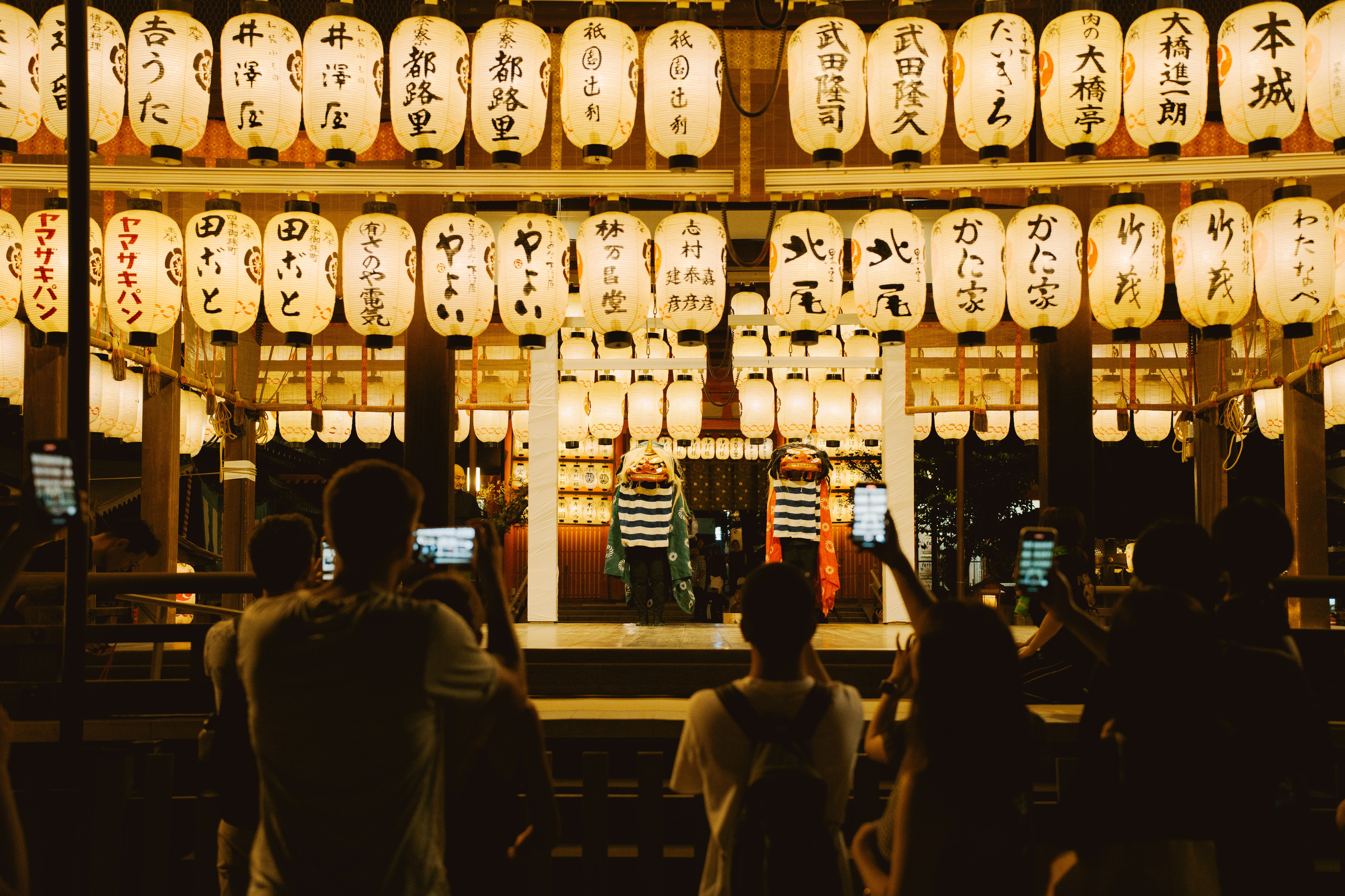 People watching illuminated japanese lanterns at night.