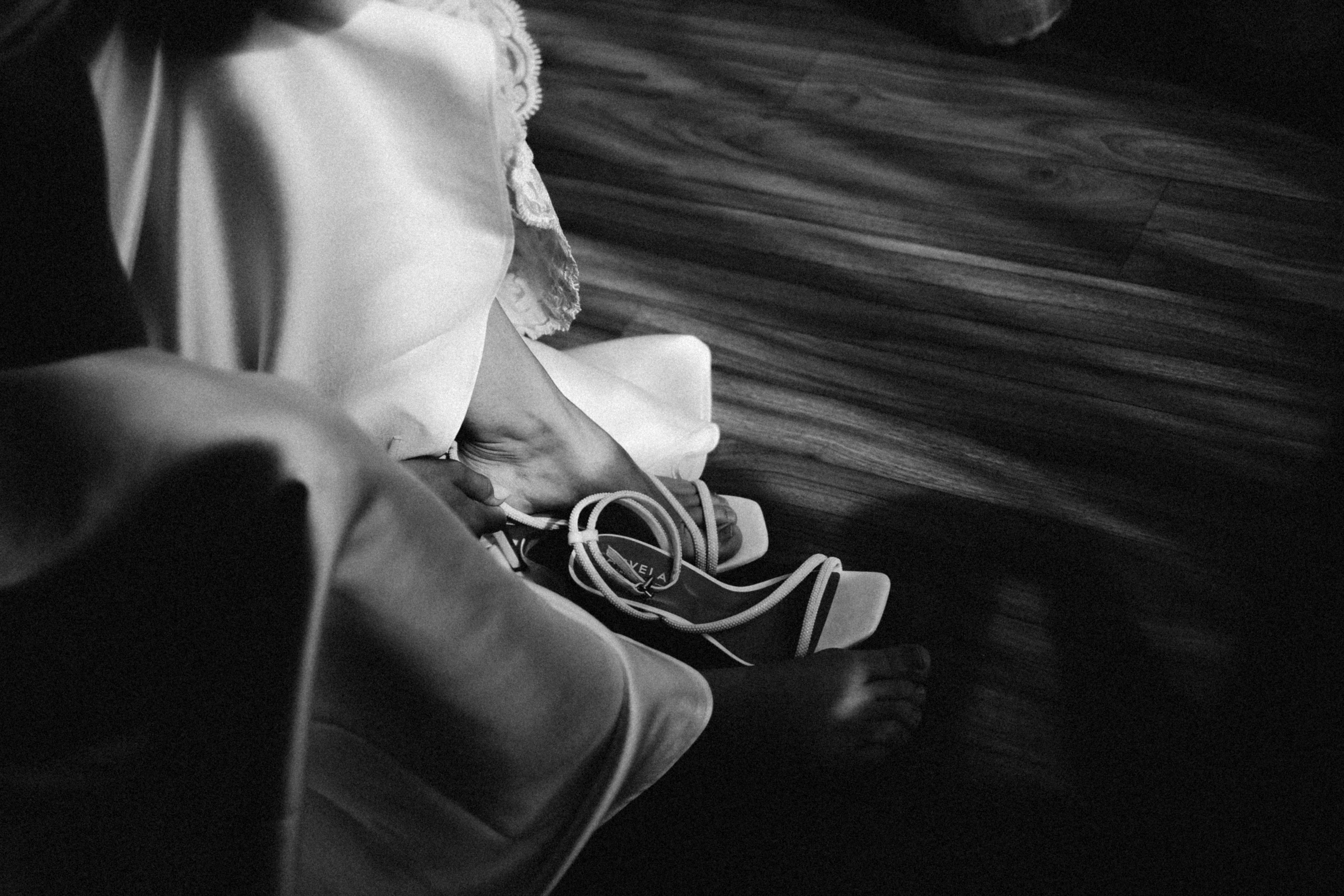 A person's hands tying shoelaces on a bed