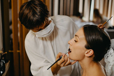 Makeup artist applying lipstick to a woman's lips
