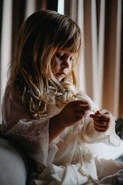 A young girl with blonde hair plays with something small.