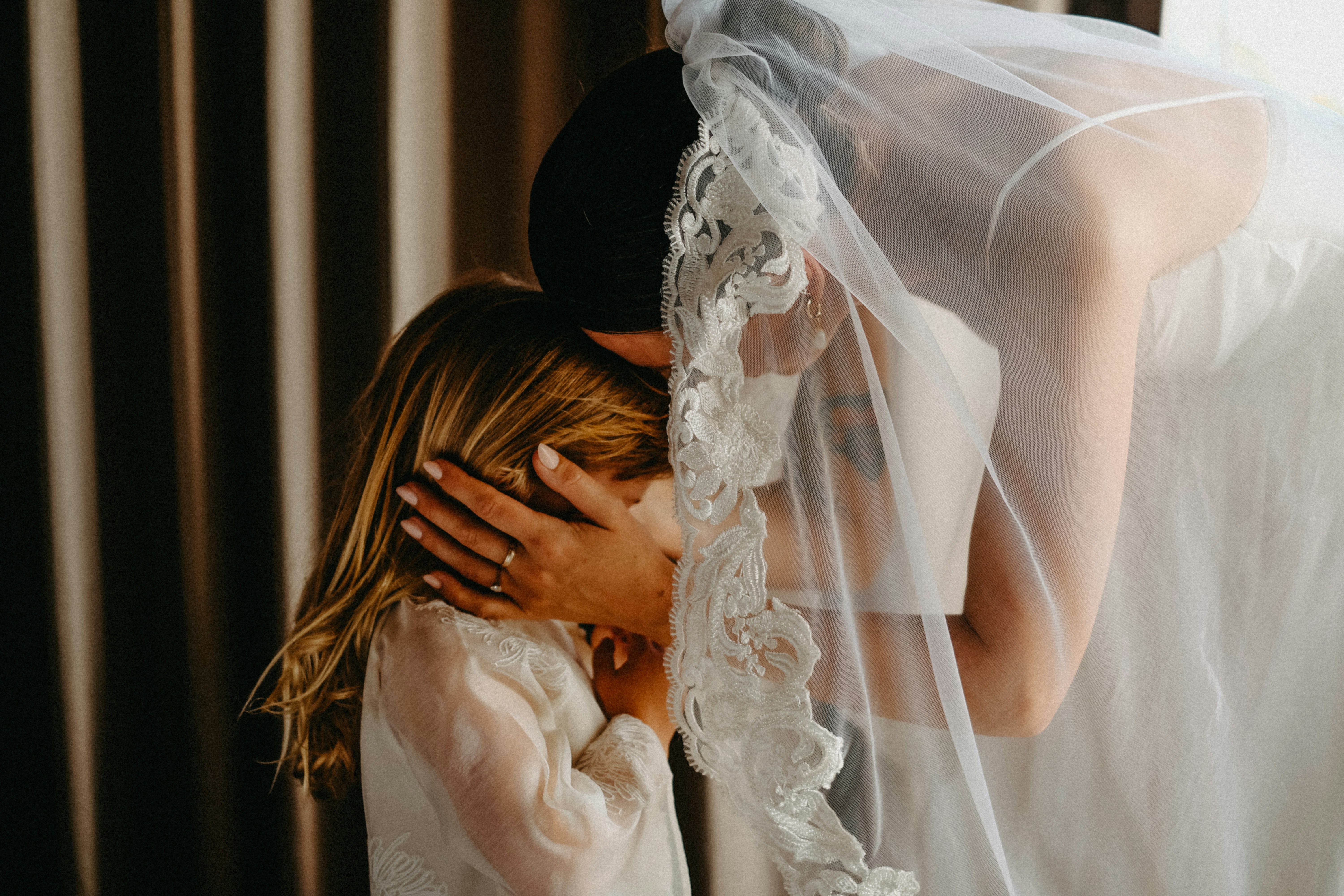 Bride hugs a young girl under her veil