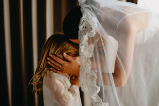 Bride hugs a young girl under her veil