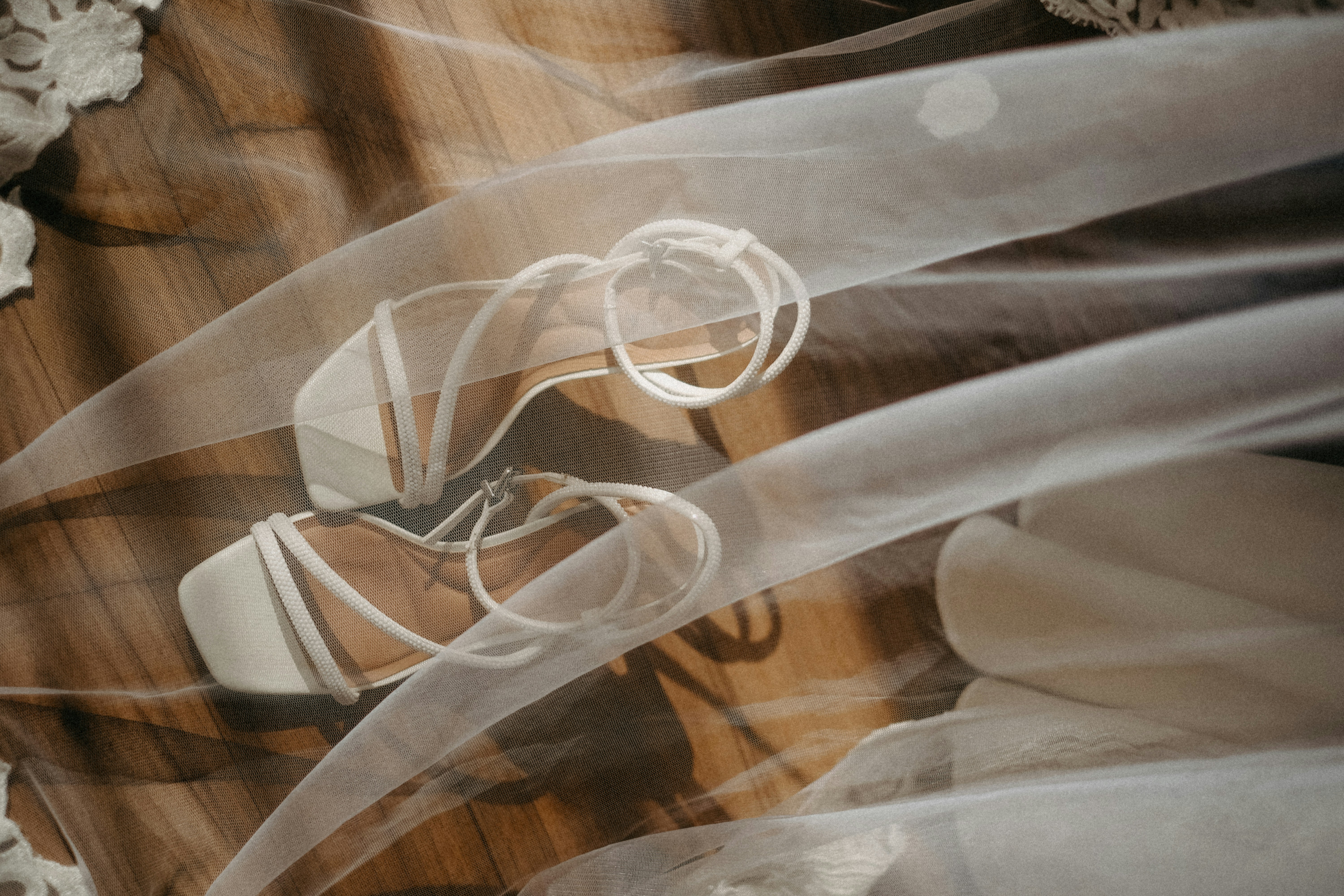 White strappy sandals with ties over wooden floor