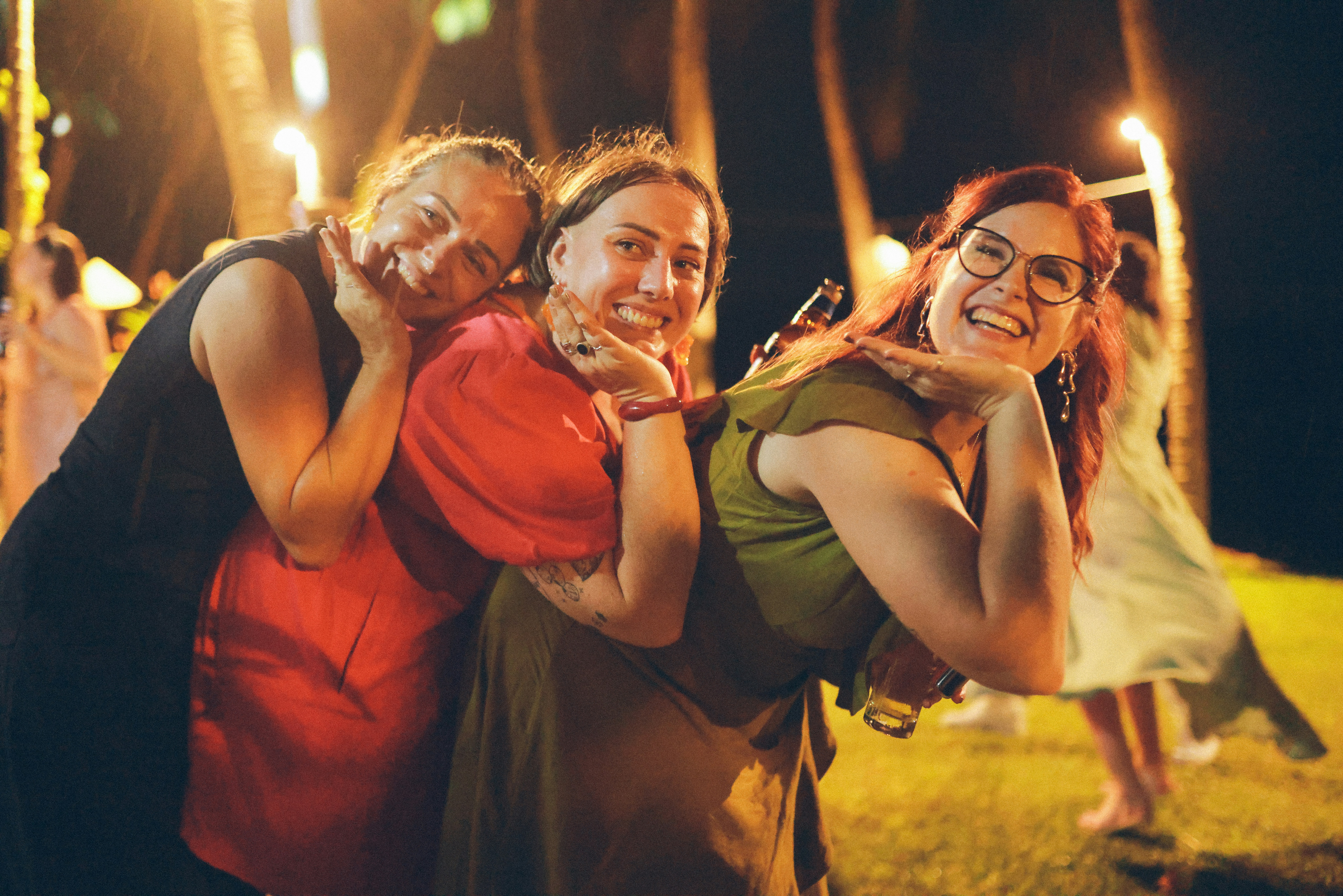 Three smiling women posing together at night