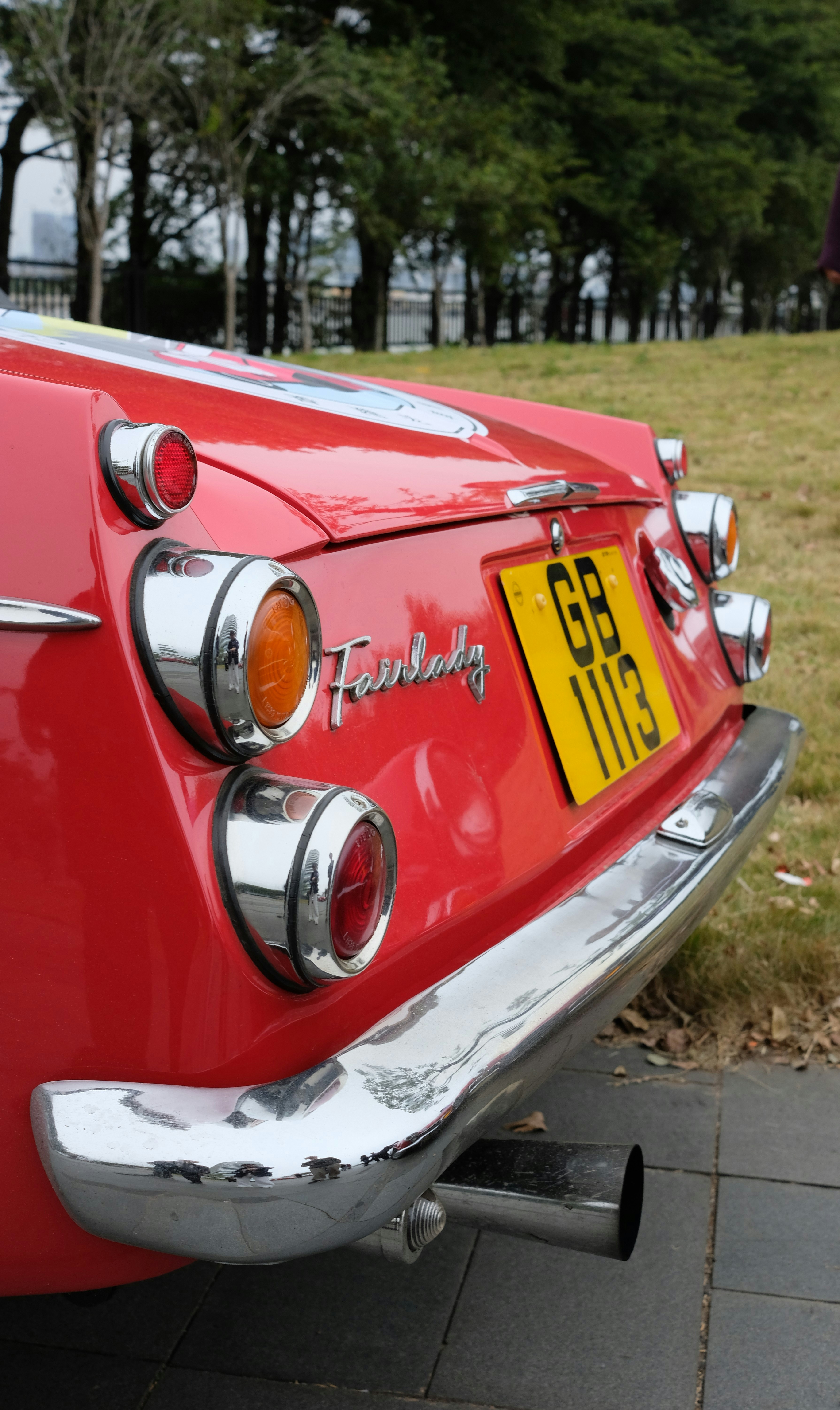 Red vintage car with chrome bumper and yellow license plate.