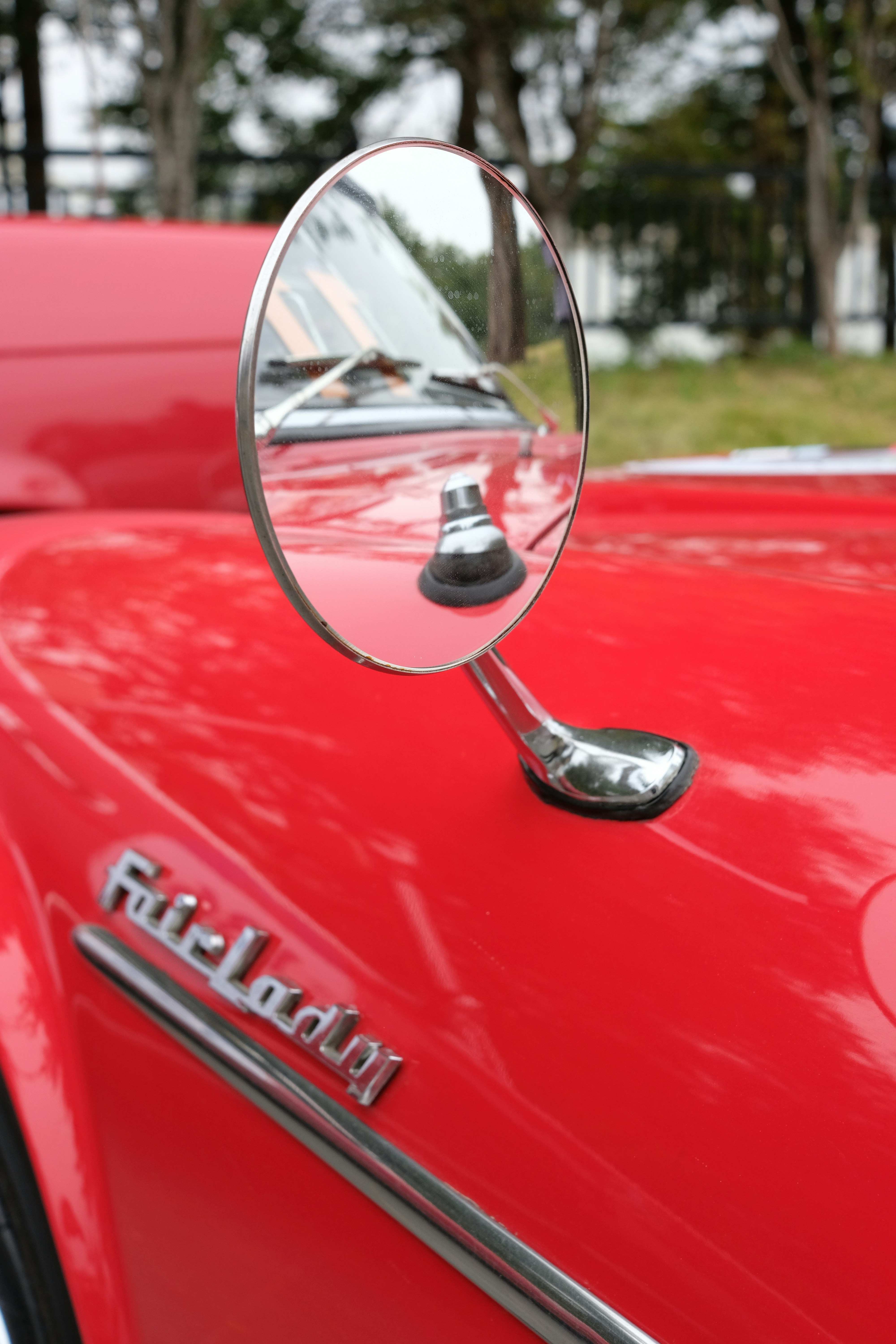 Close-up of a vintage red car's side mirror.