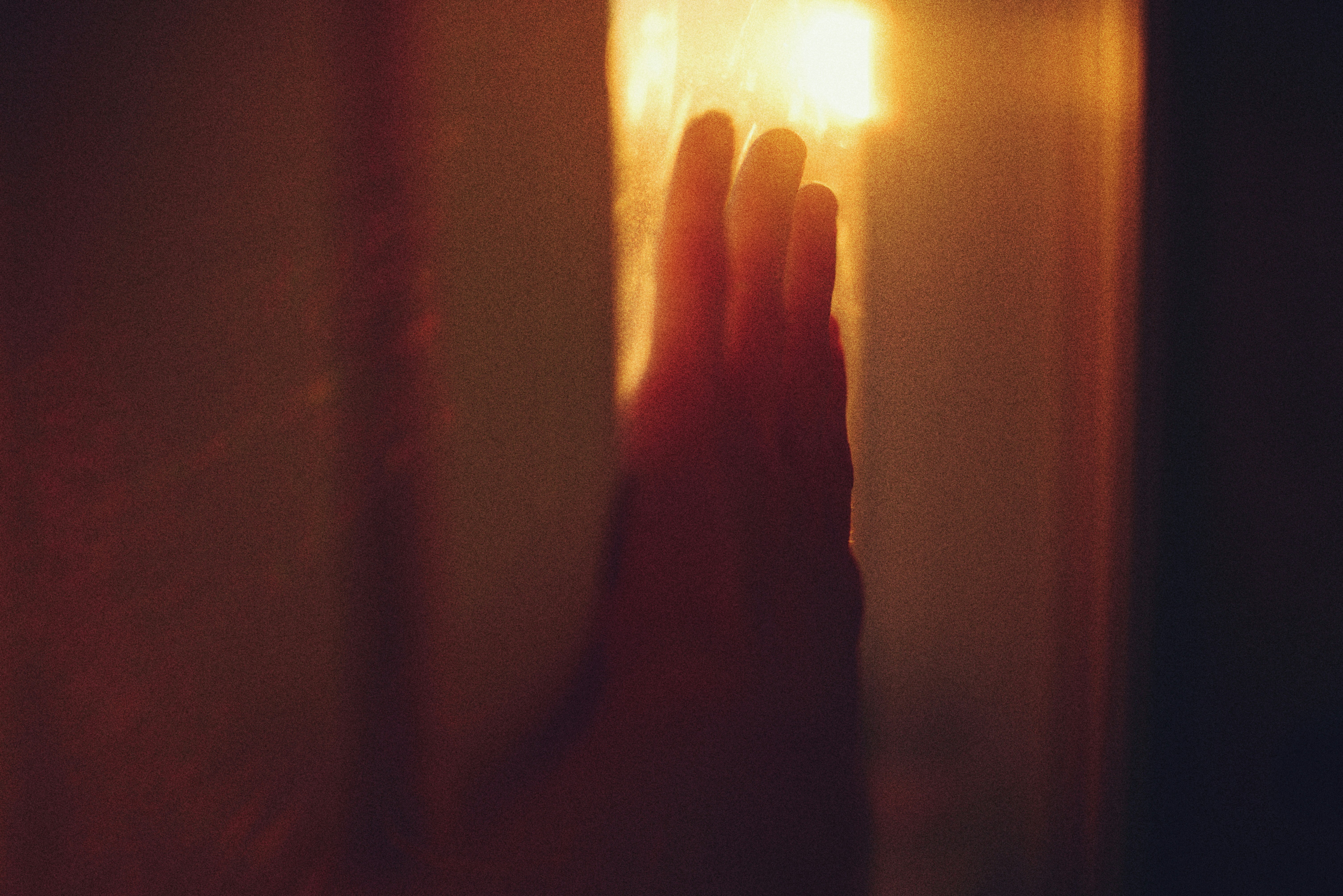 A hand reaching towards a bright light source.