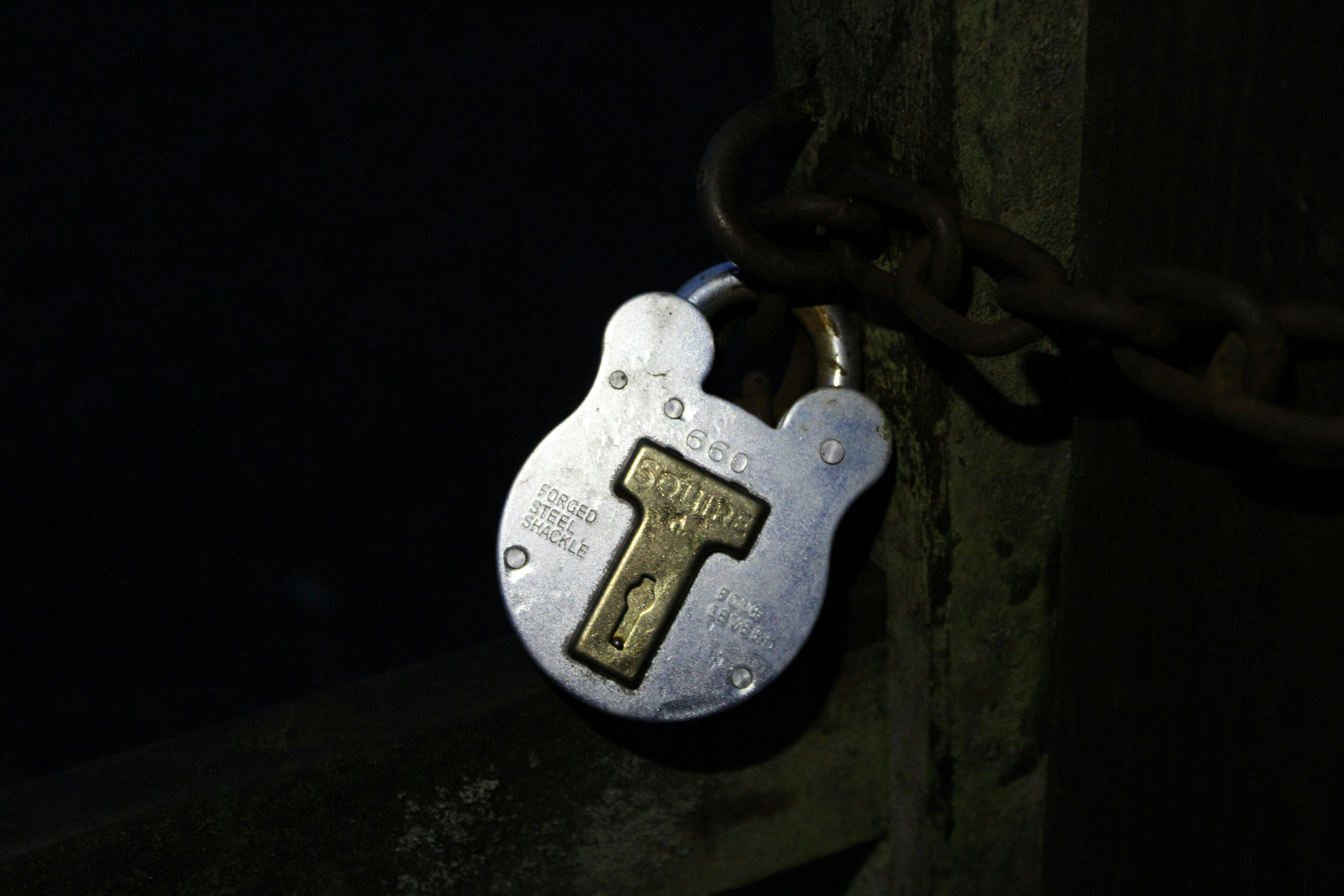 A vintage padlock secured to a rusty chain.