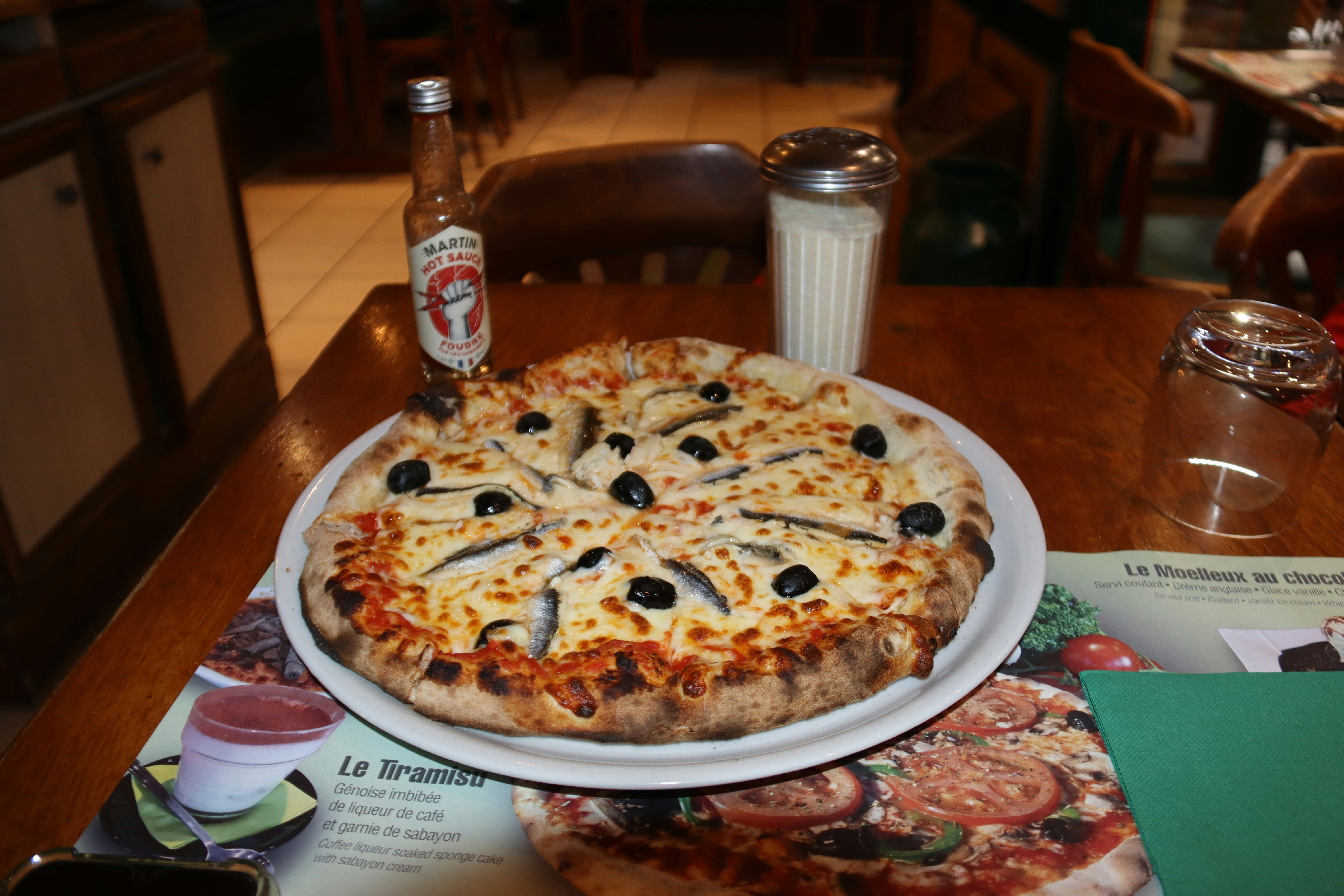 Pizza with anchovies and olives on a table.