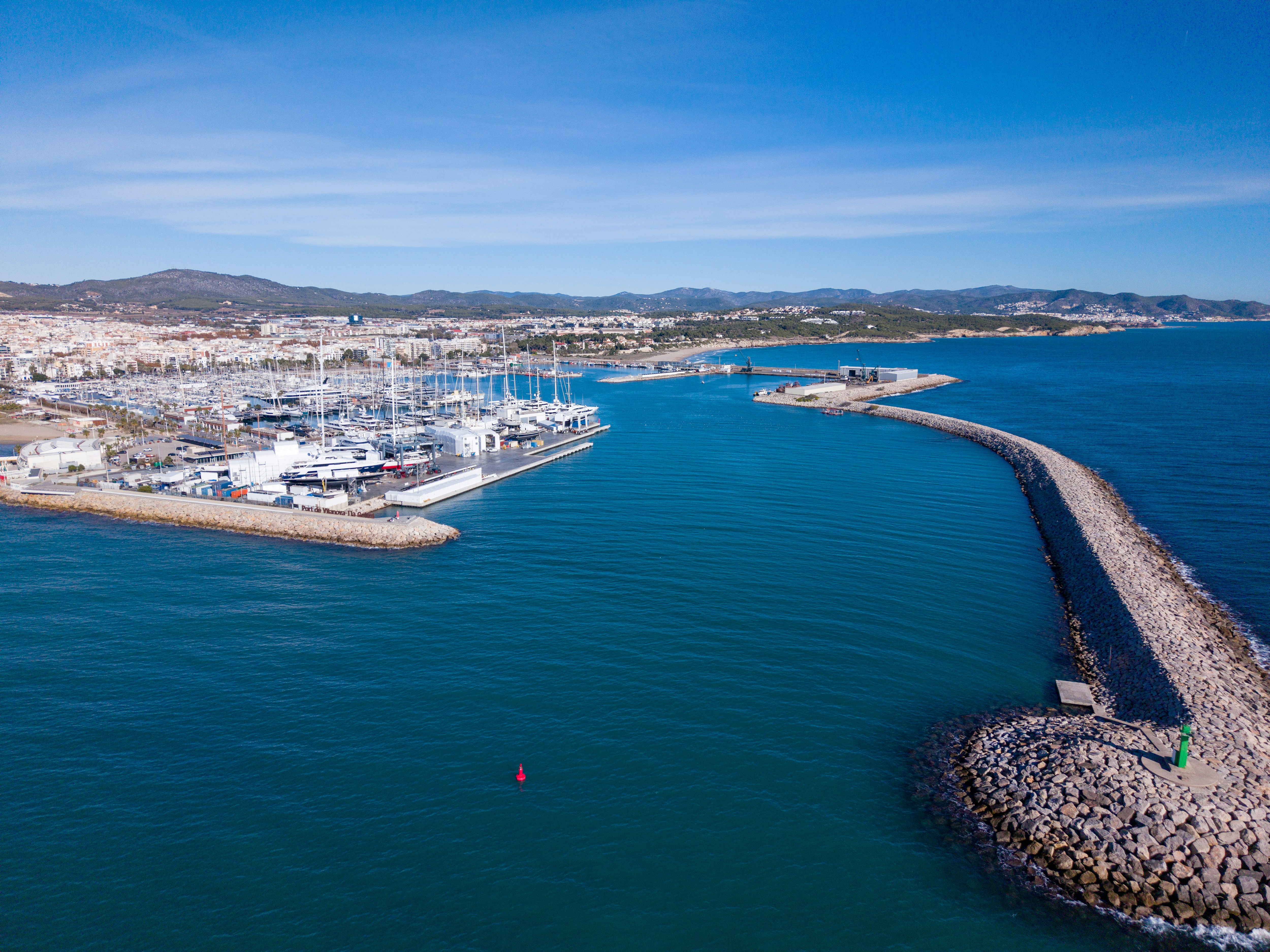 Boote legten in einem Yachthafen mit einem langen steinernen Wellenbrecher an.