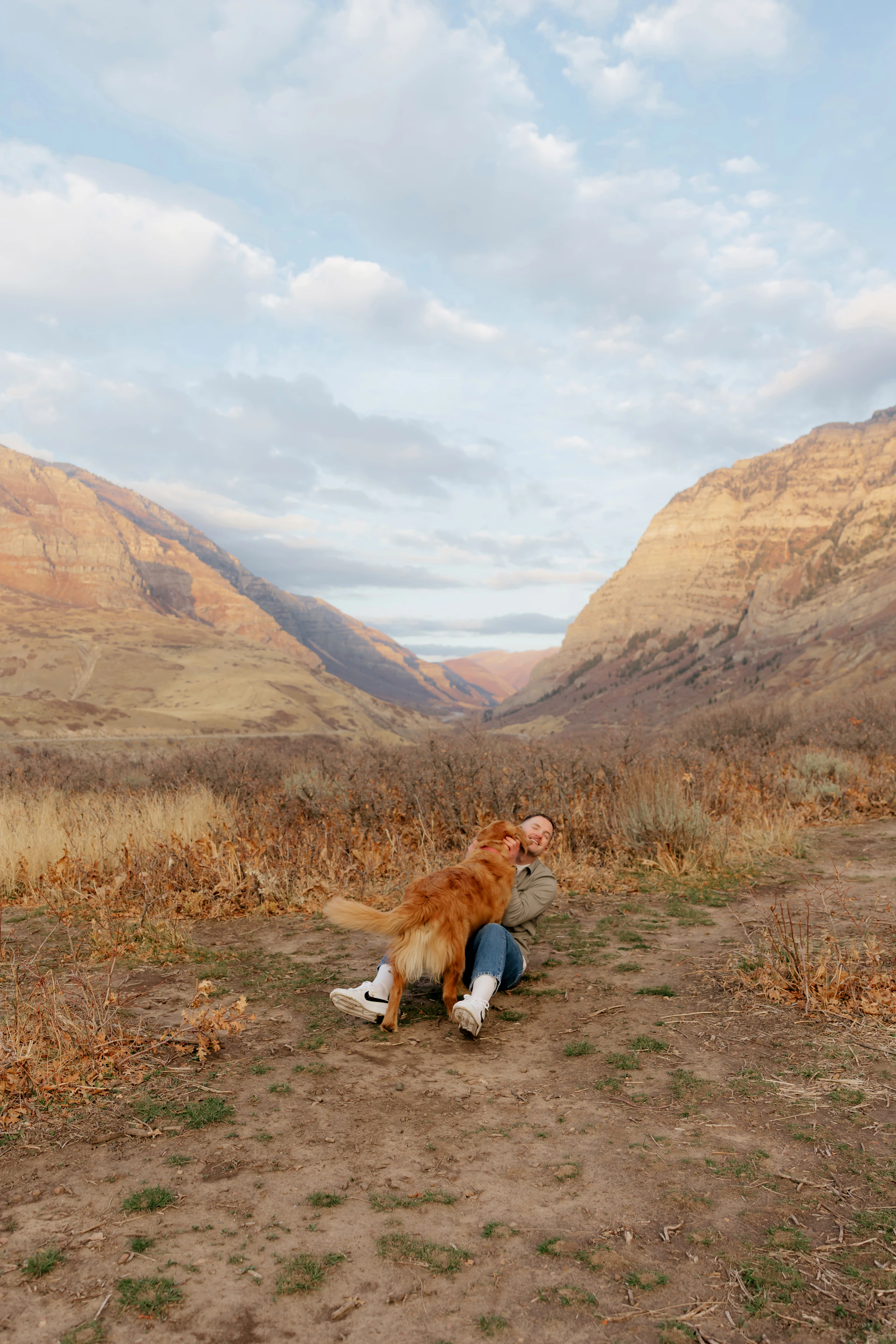 Woman hugging a golden retriever in a mountain valley