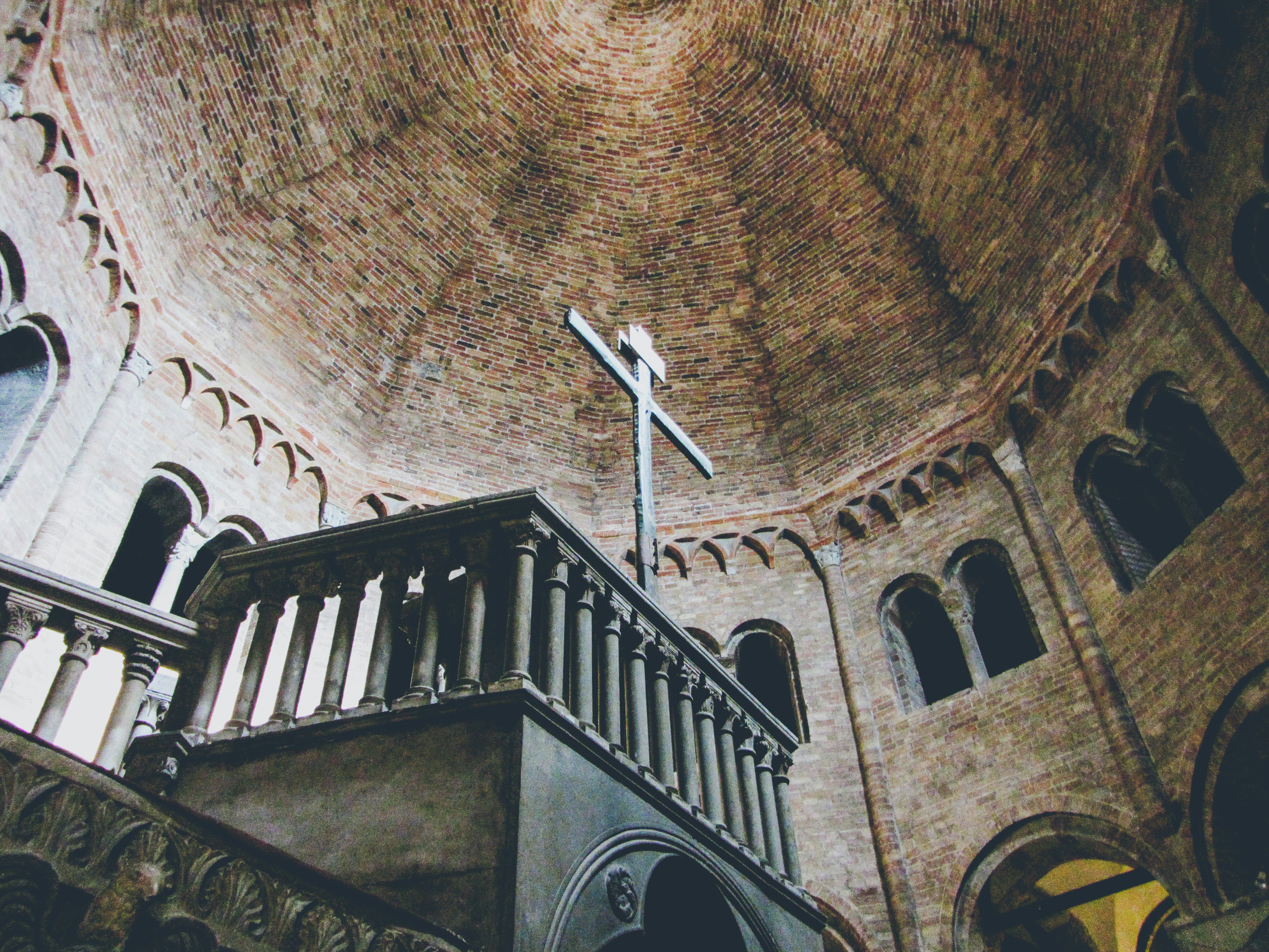 A cross inside a domed building with arched windows.