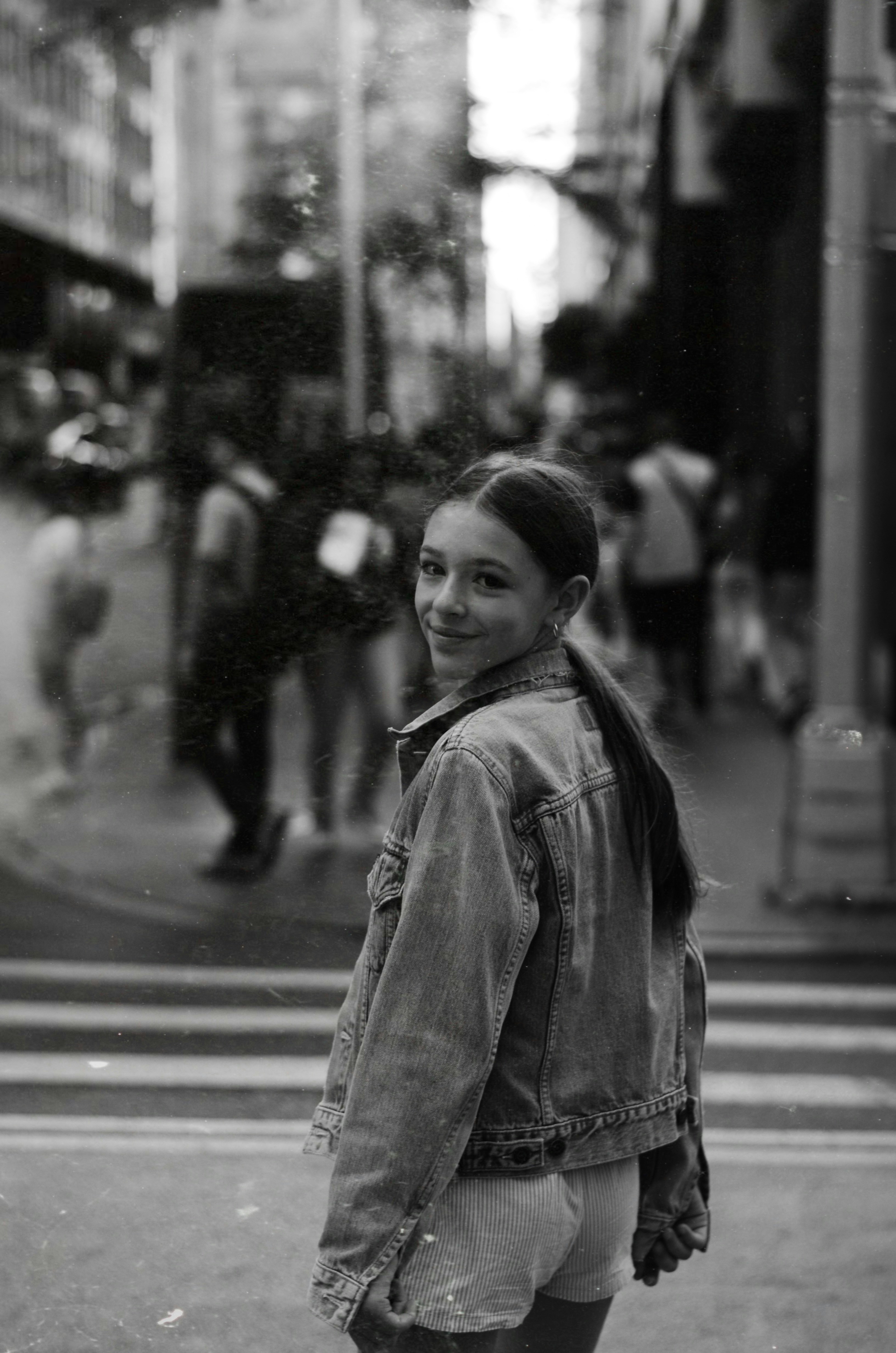 Junge Frau in Jeansjacke überquert die Straße