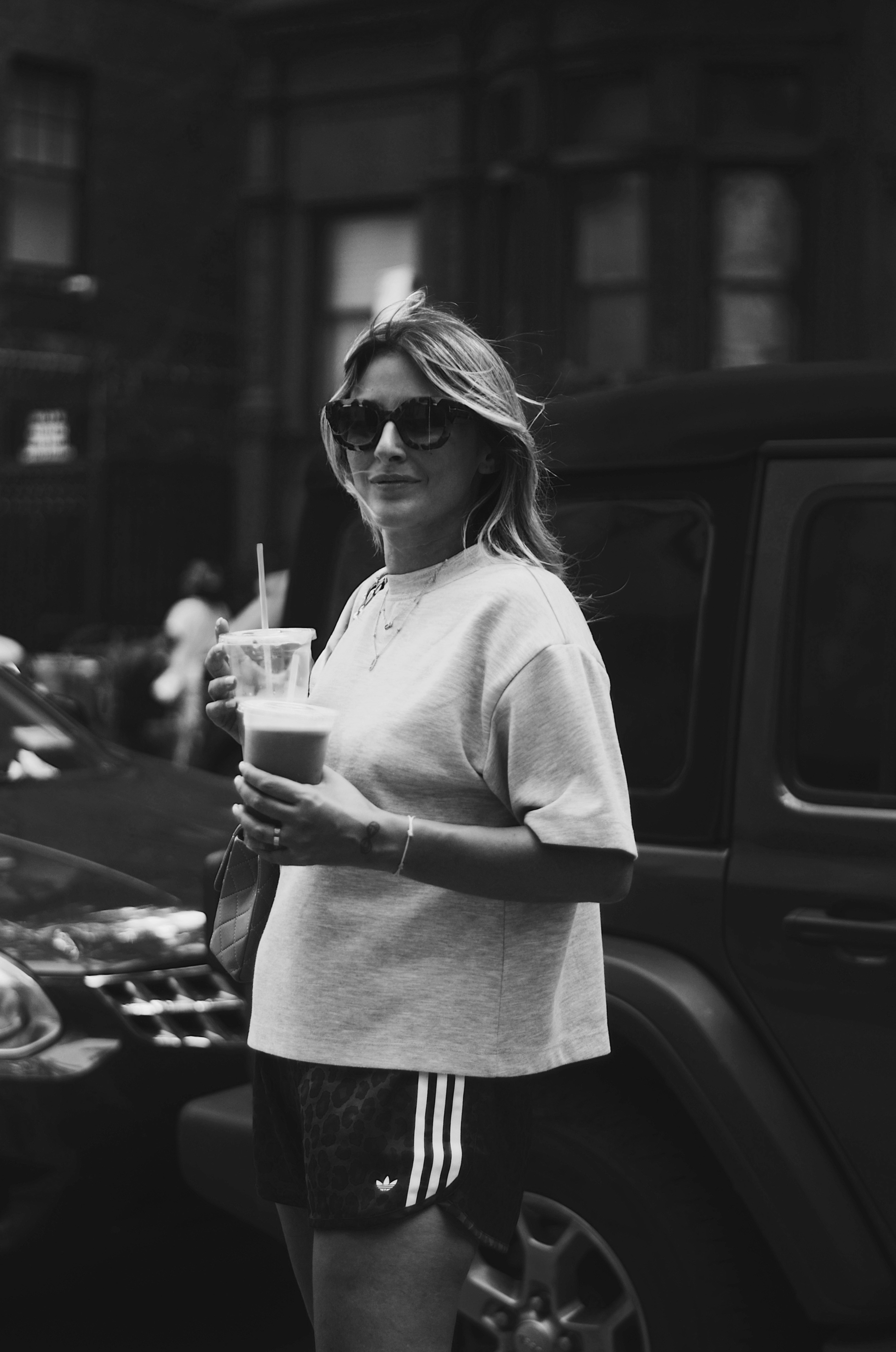 Frau, die ein Getränk auf einer Stadtstraße hält.