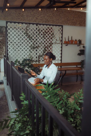 A woman sits at a table outdoors, working on papers.