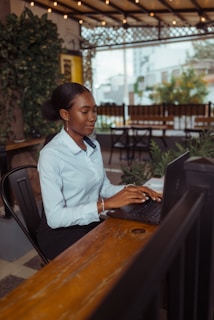 A woman typing on a laptop at an outdoor cafe.