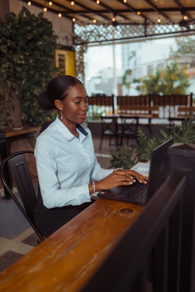 A woman typing on a laptop at an outdoor cafe.