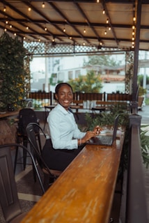 A smiling woman works on a laptop at a cafe.
