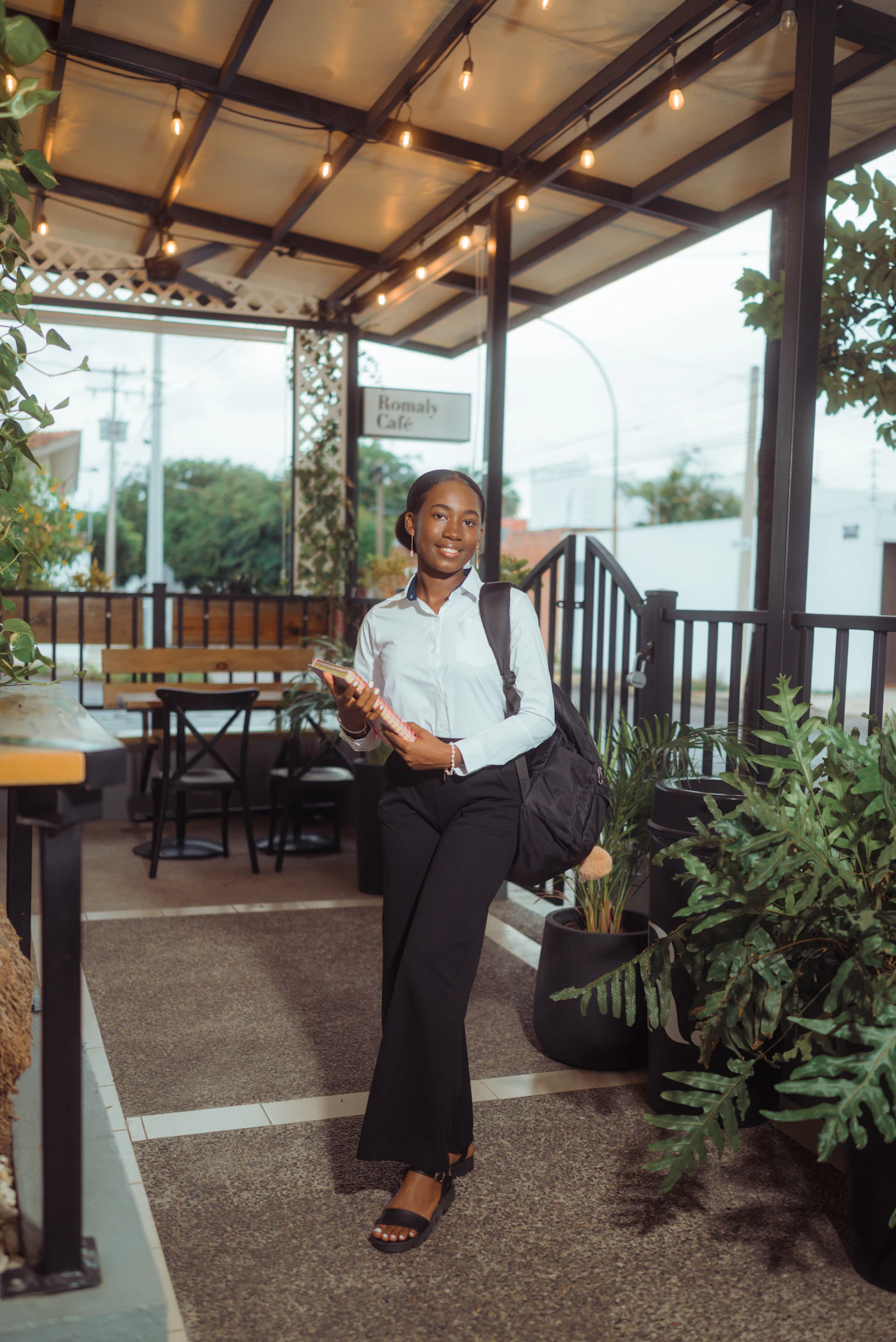 Emprendedora sonriendo con una carpeta fuera de un café