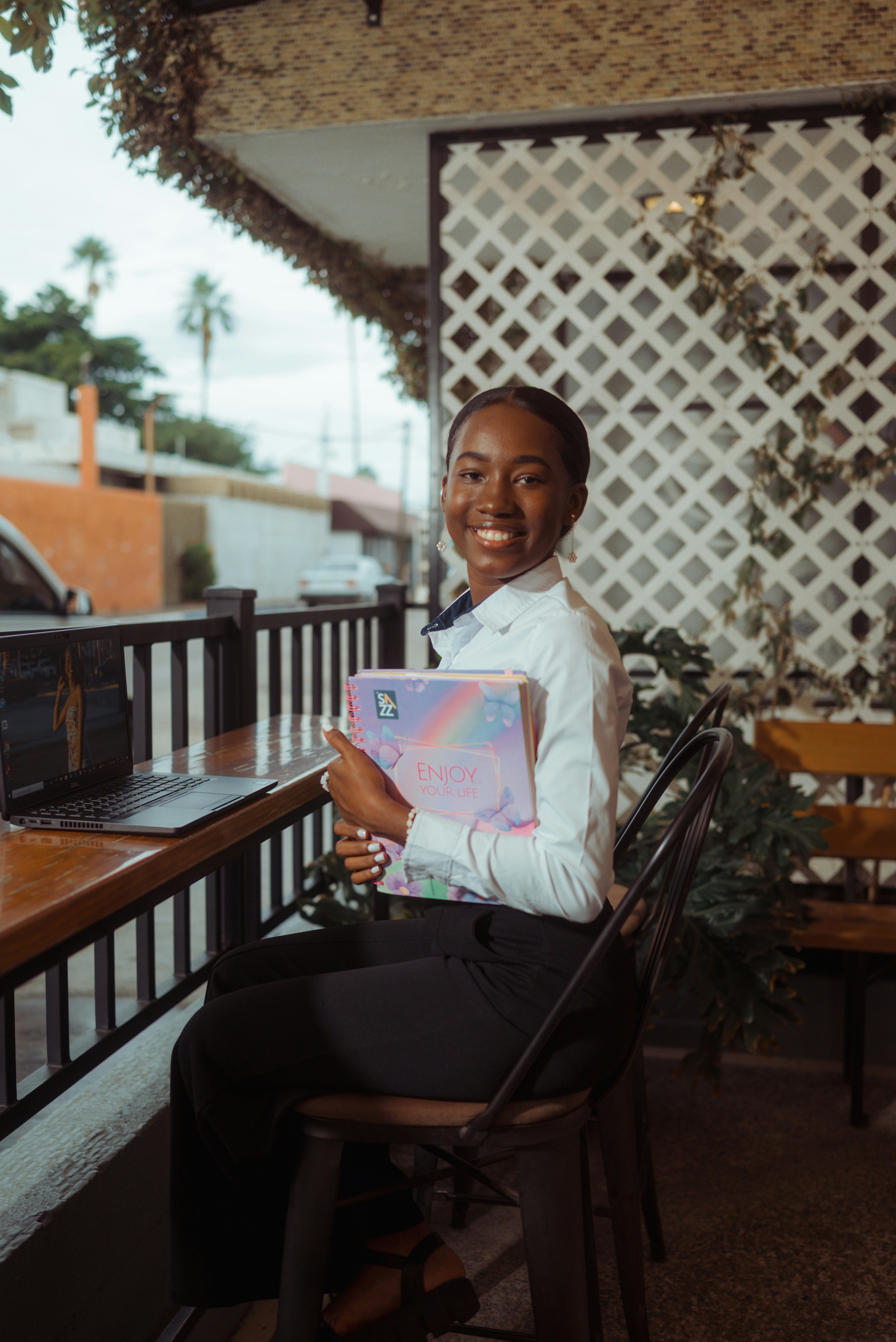 Young woman smiling holding a planner at a table.