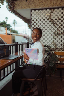 Young woman smiling holding a planner at a table.