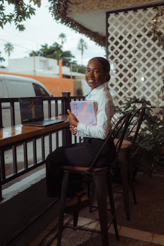 Young woman smiling with books and laptop at cafe