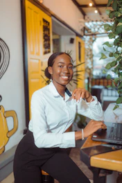 A smiling woman in a white shirt at a laptop